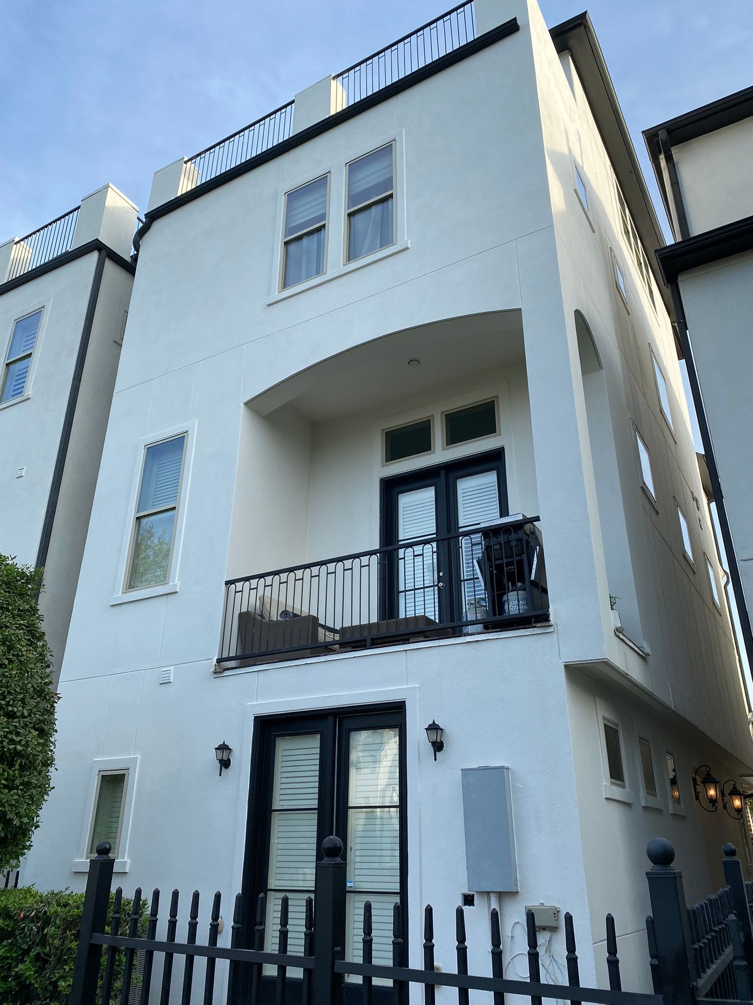 A white house with a balcony and a fence in front of it.
