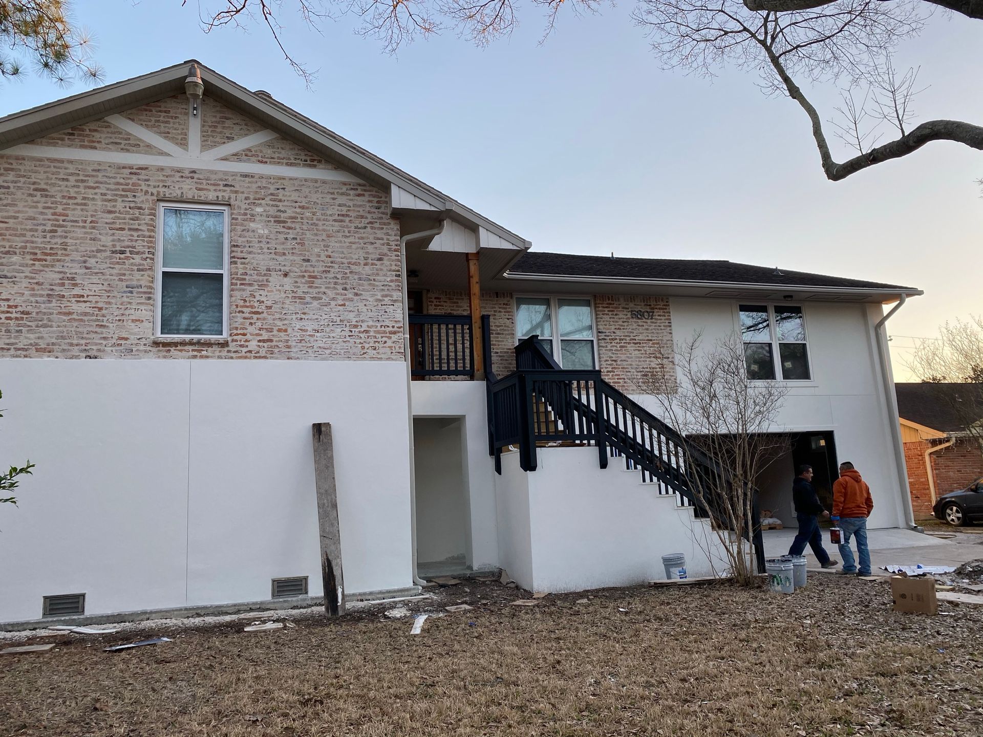 A couple of people are standing in front of a large brick house.