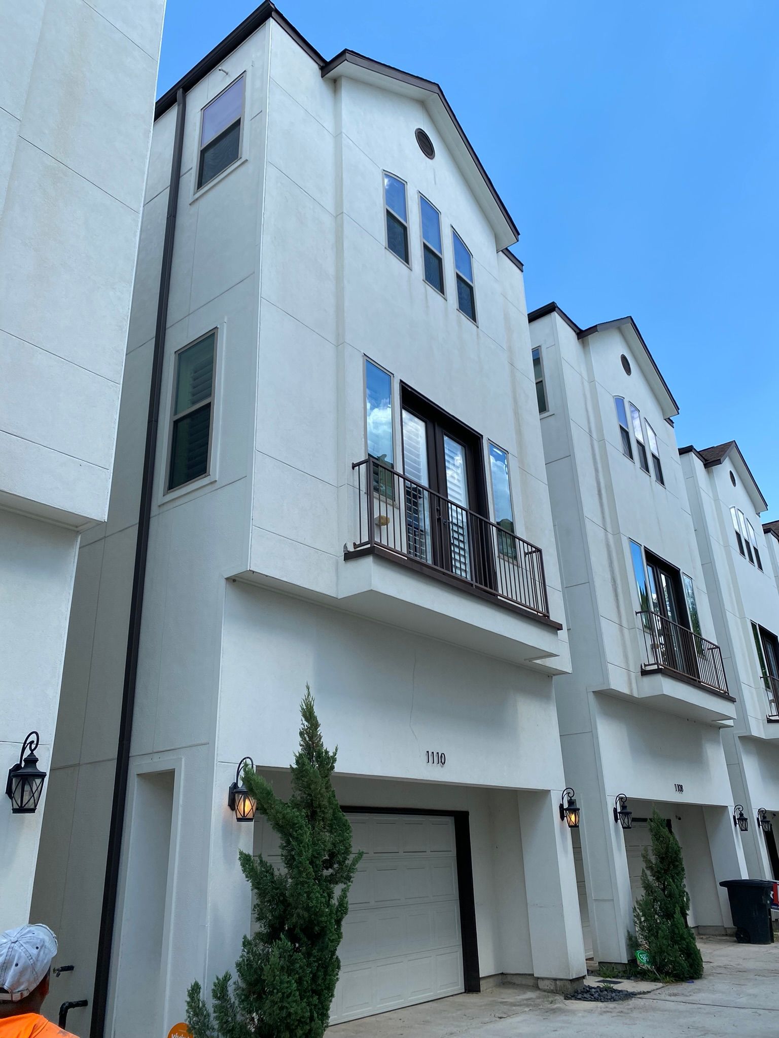 A man is standing in front of a white apartment building.