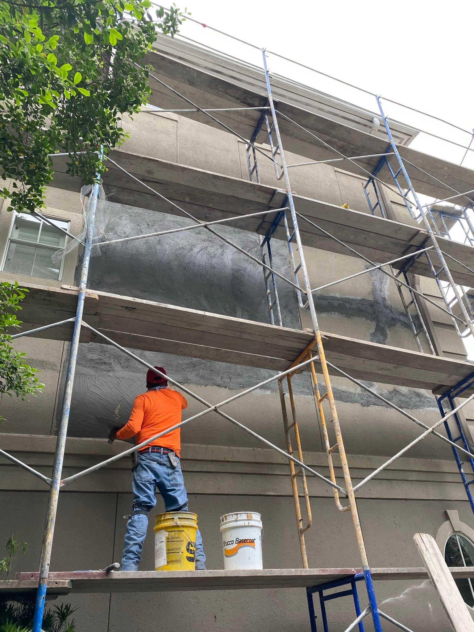 A man is standing on a scaffolding painting a building