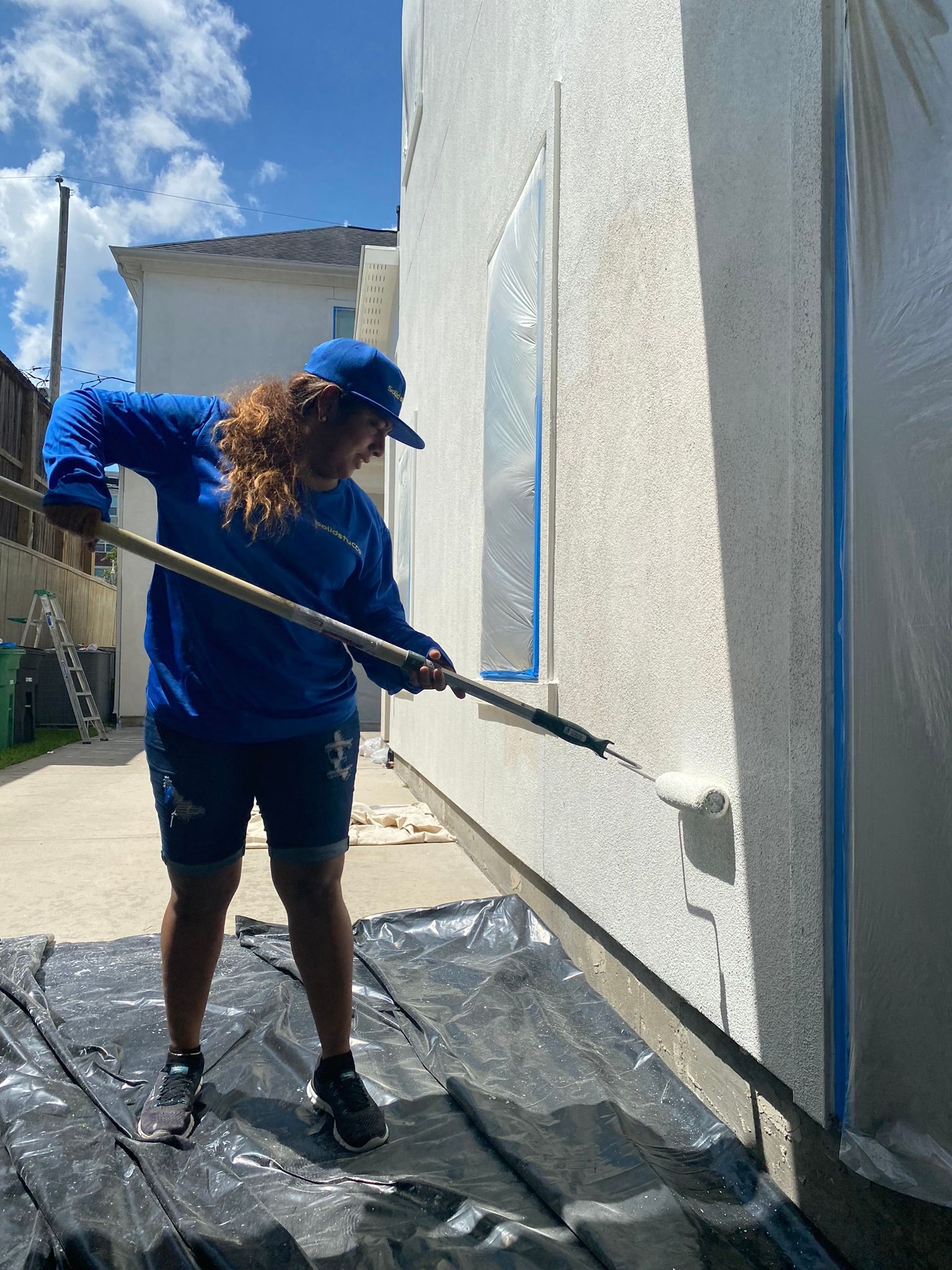 A woman is painting a wall with a roller.