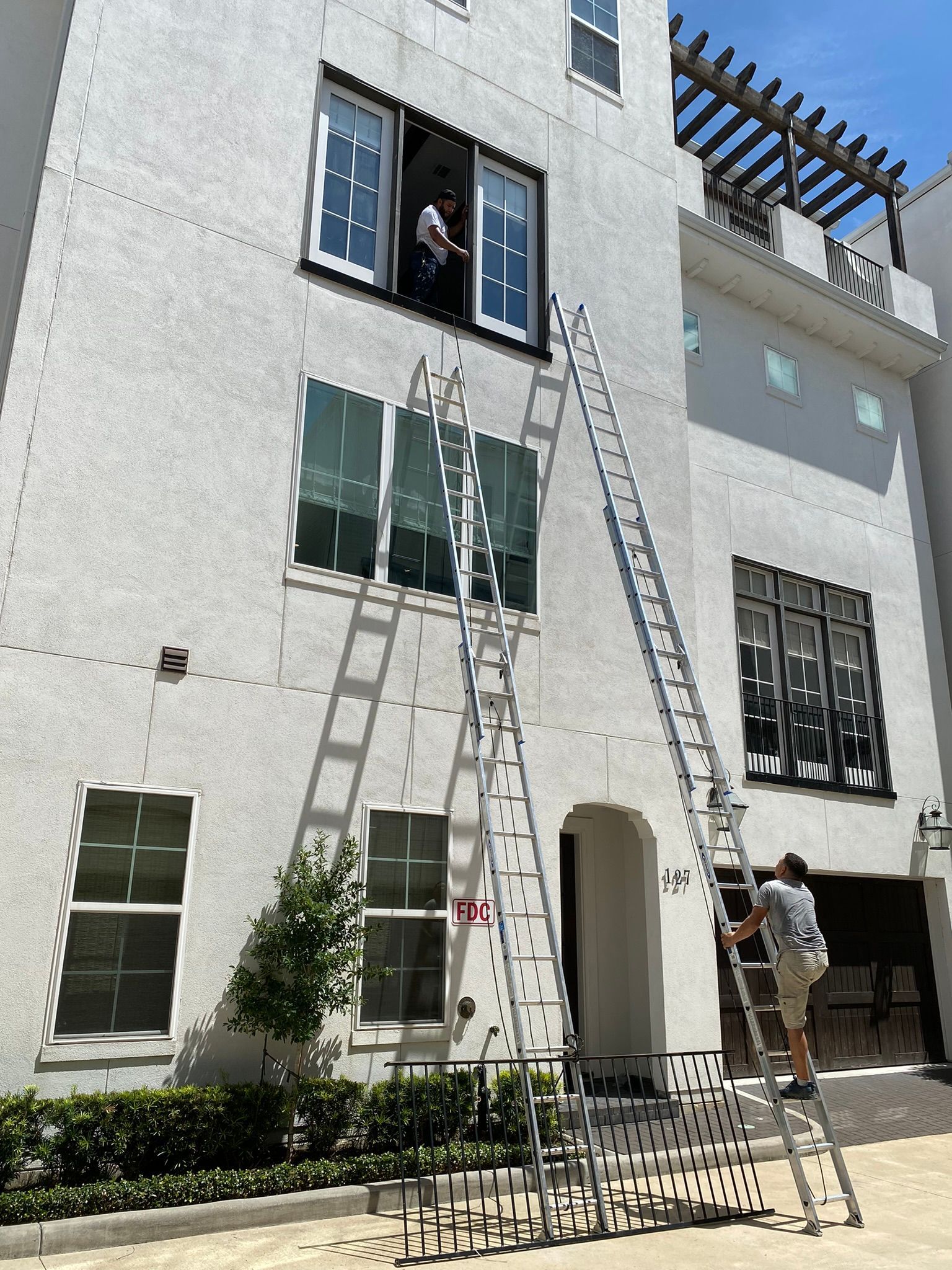 A man is cleaning the windows of a building with a ladder.