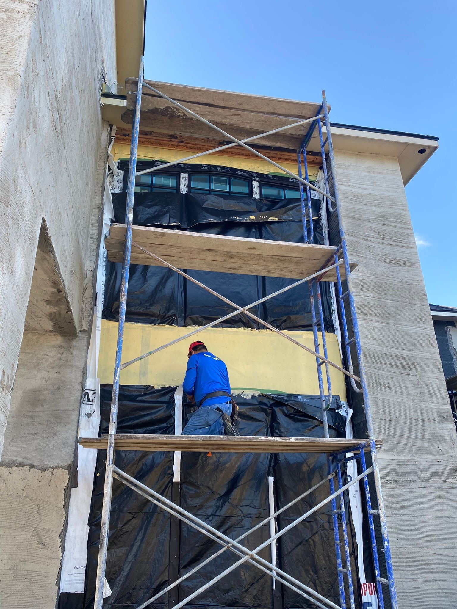 A man is standing on a scaffolding on the side of a building.