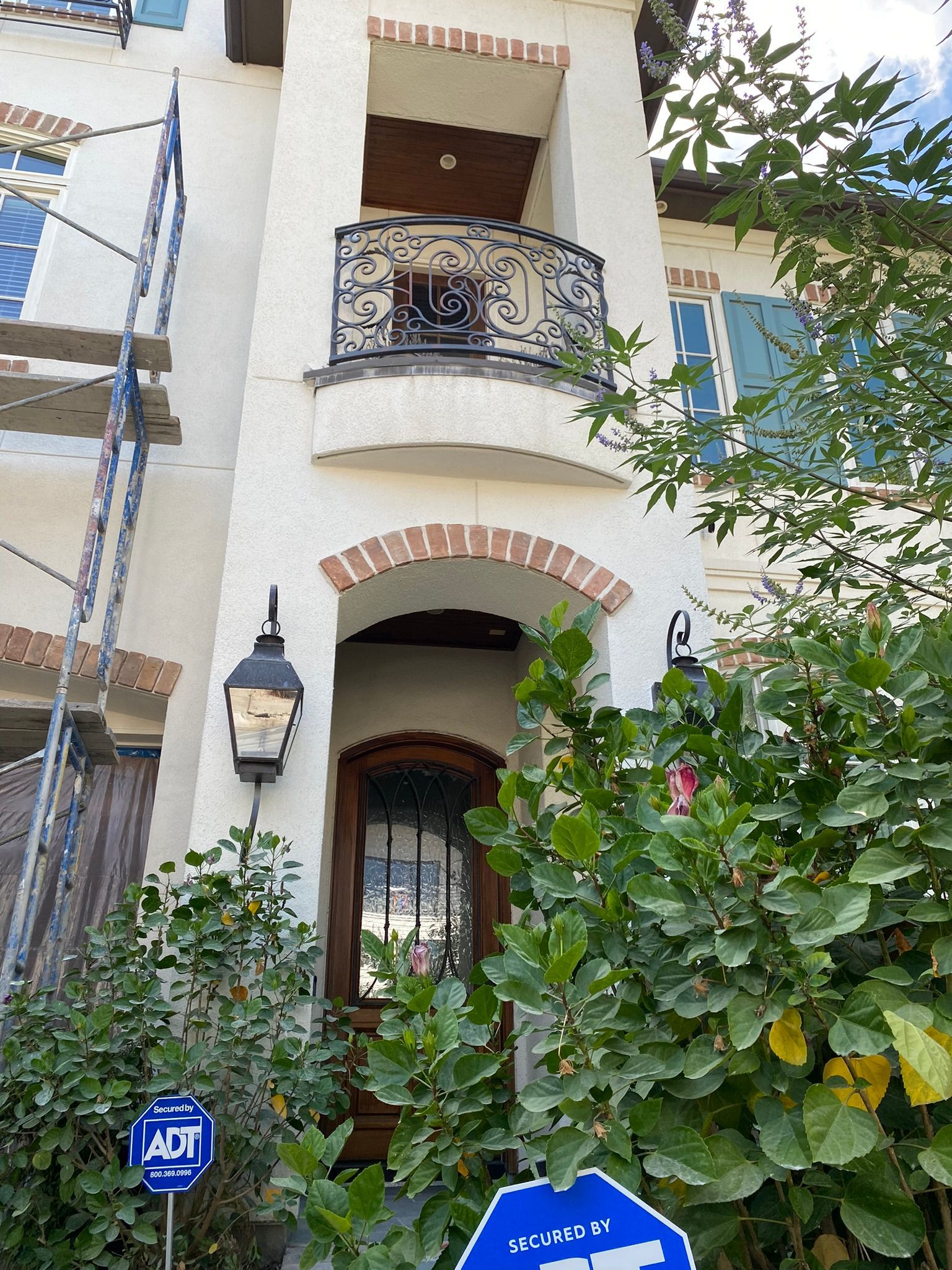 A white house with a balcony and a blue sign in front of it.