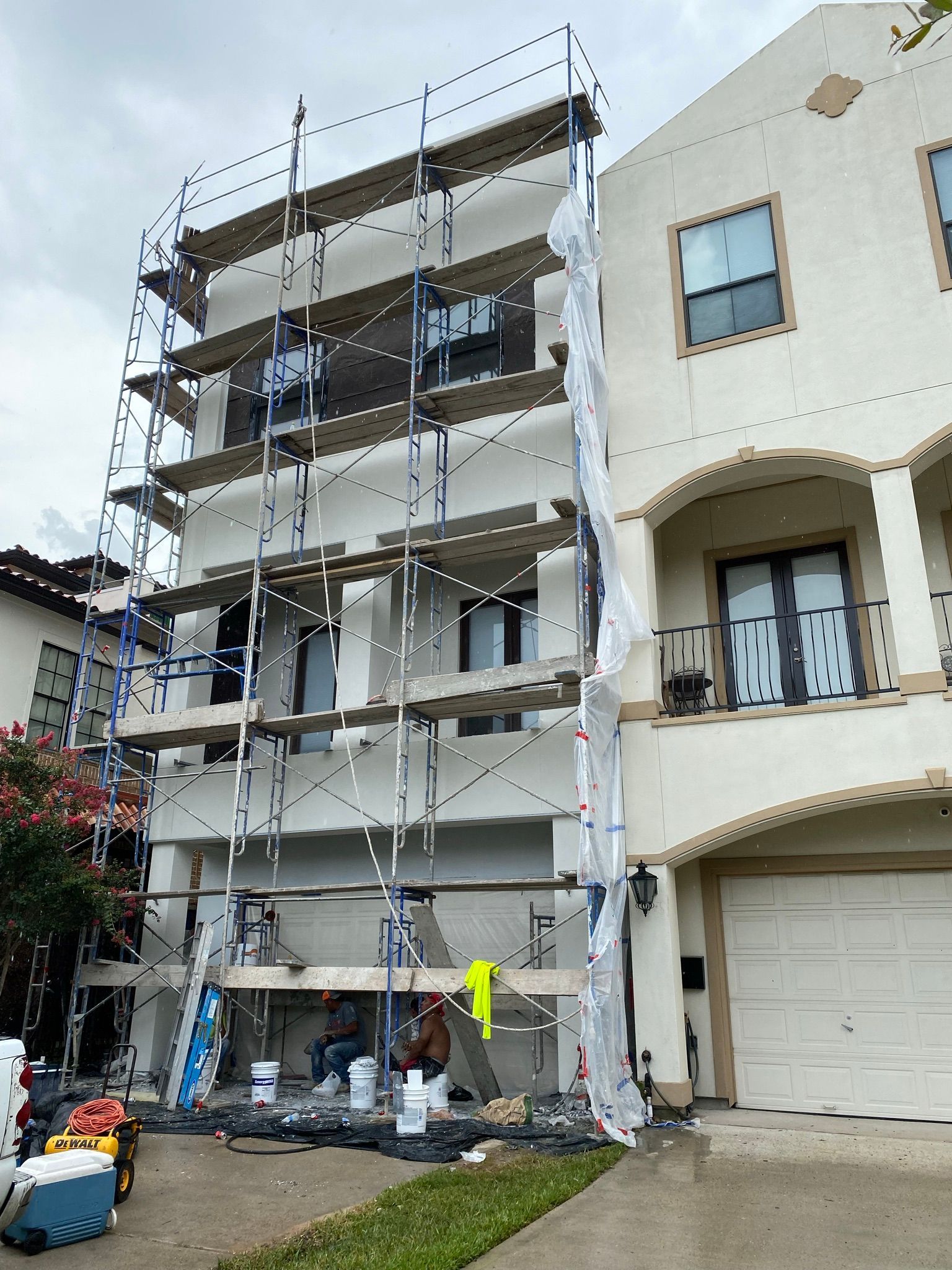 A large white house is being painted with scaffolding.