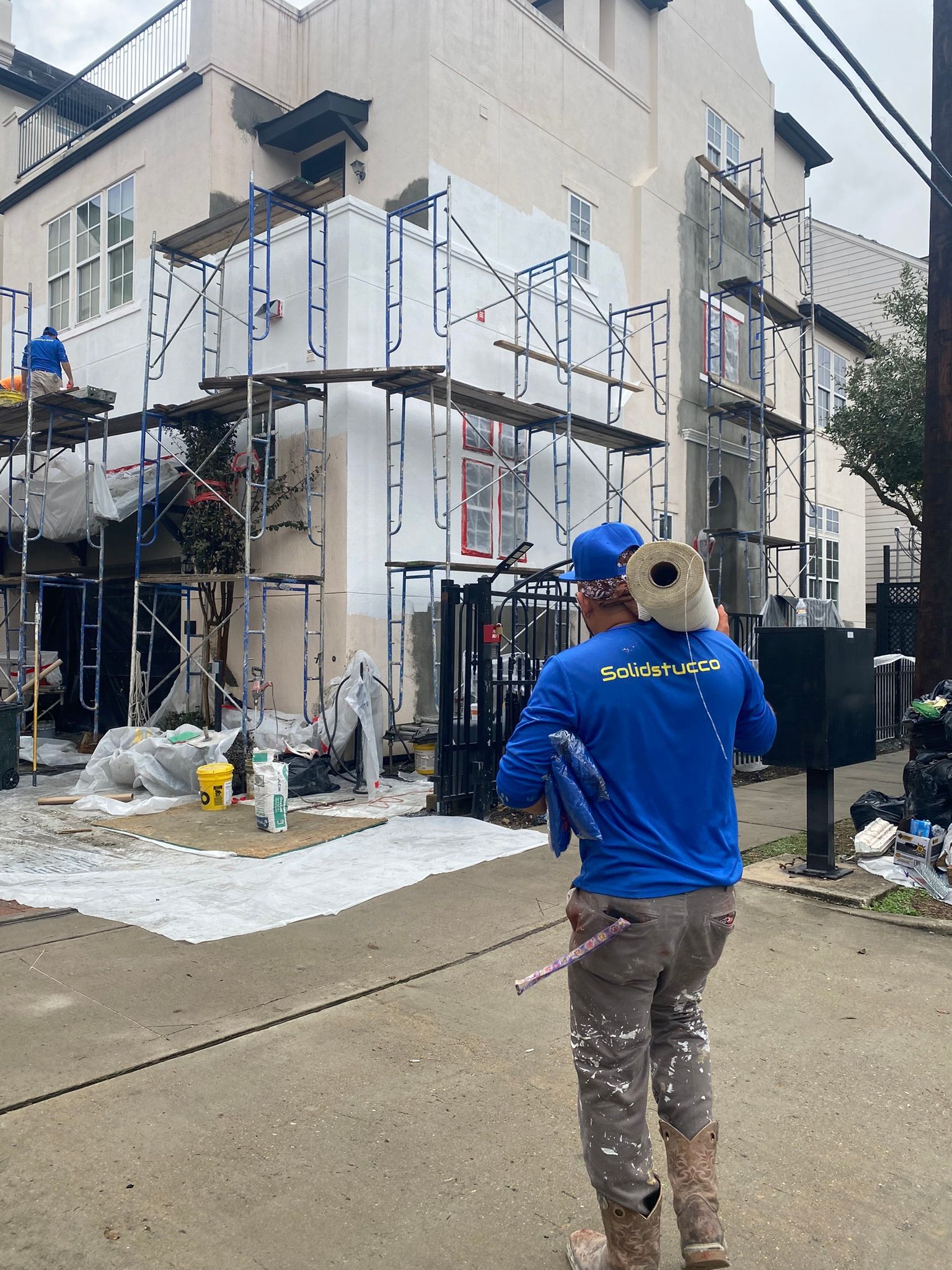 A man is standing in front of a building that is being painted.