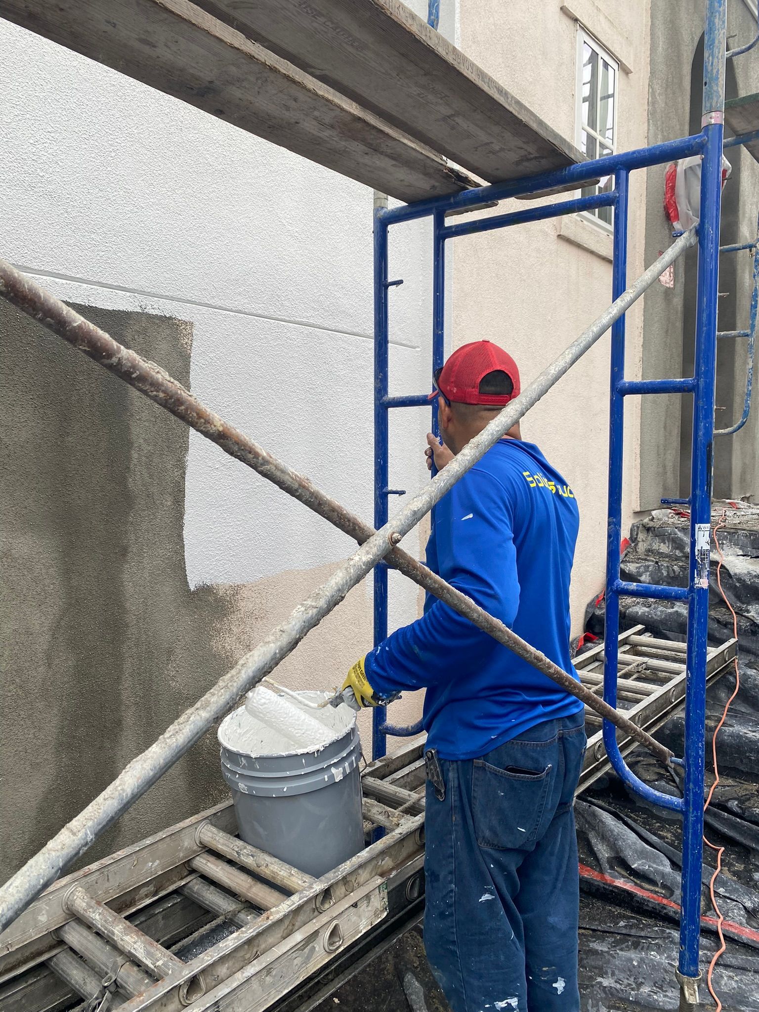 A man is standing on a scaffolding painting a wall.