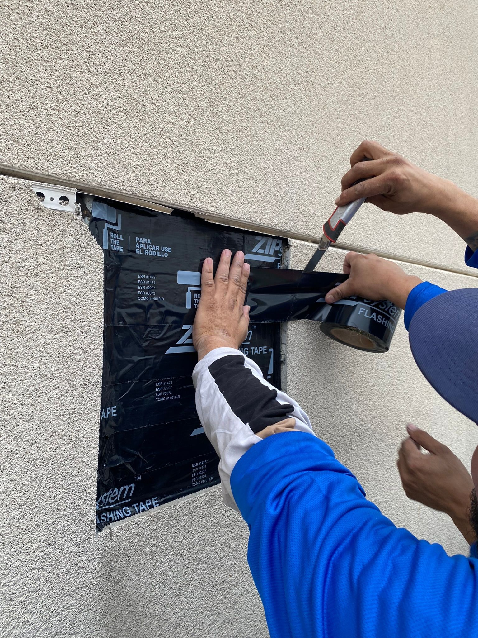 A person is cutting a piece of tape on a wall.