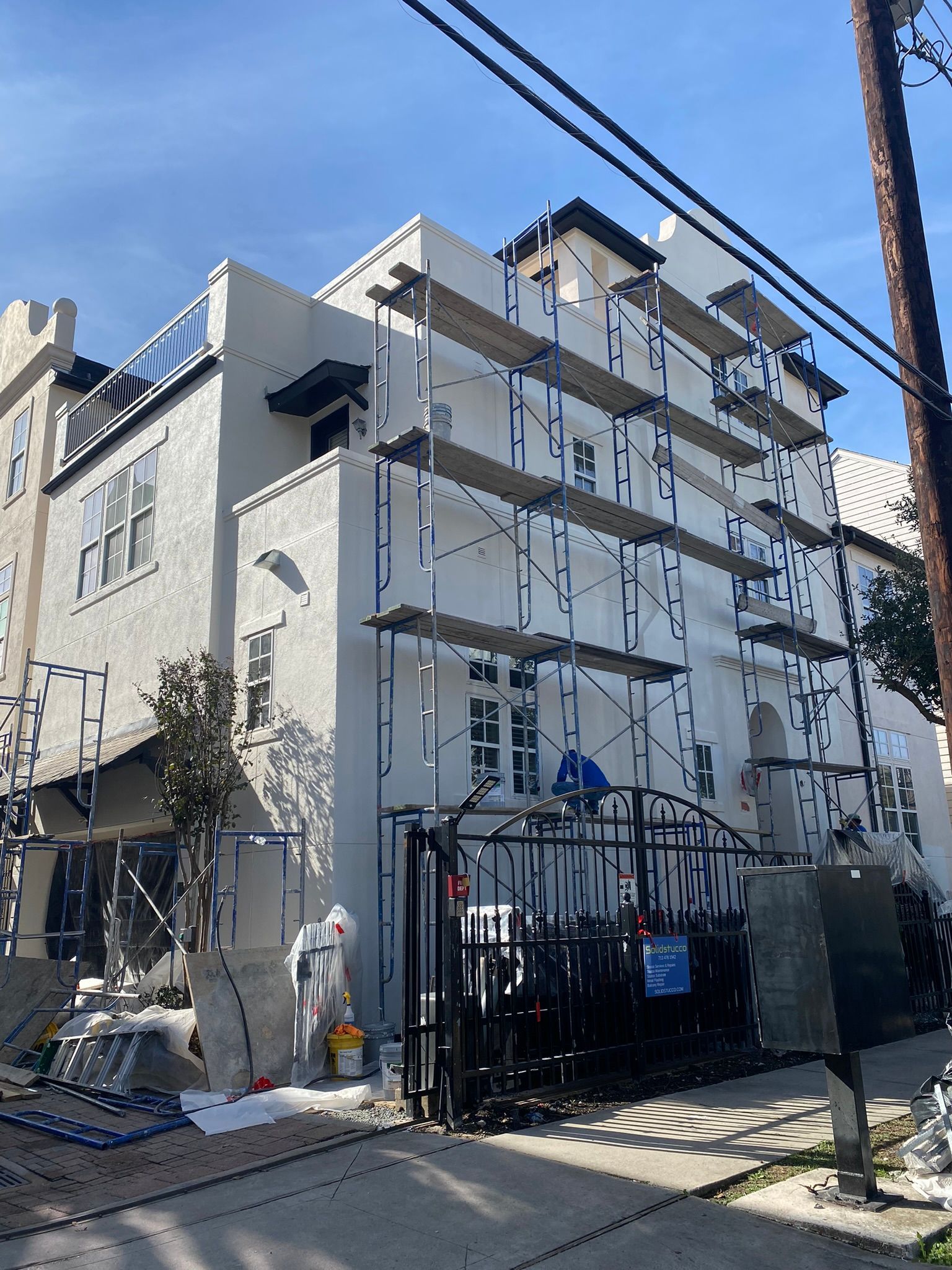 A large white building is being painted with scaffolding.