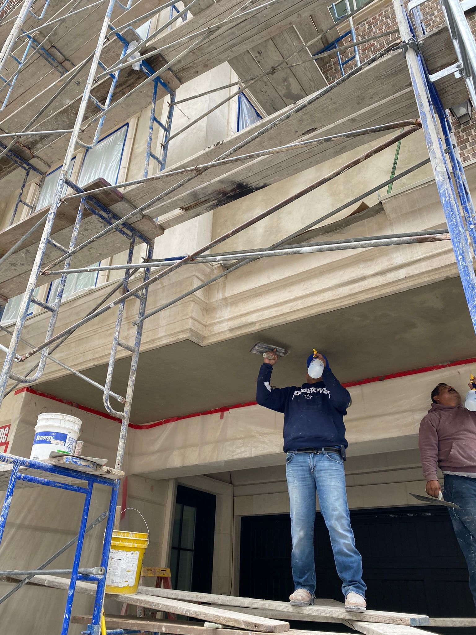 A man wearing a mask is working on the ceiling of a building under construction.