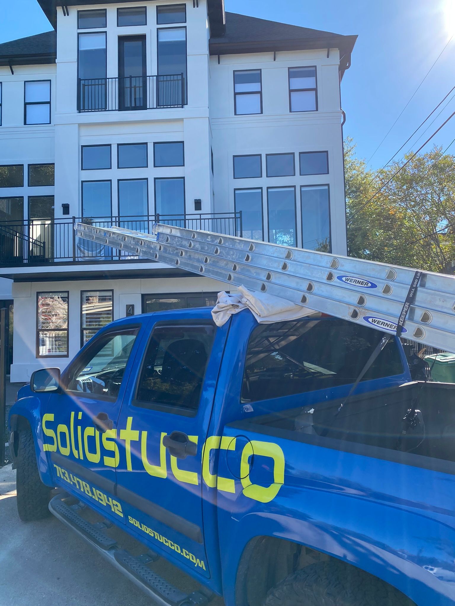 A blue truck with soliducco written on the side is parked in front of a building
