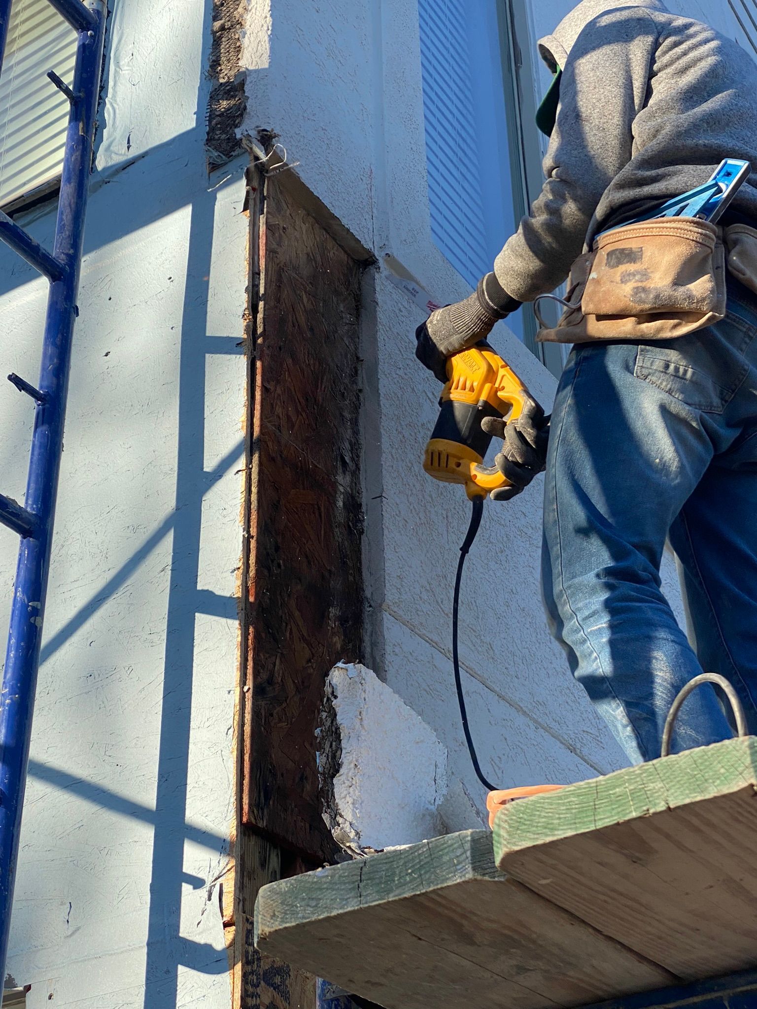 A man is using a drill to cut a hole in a wall.