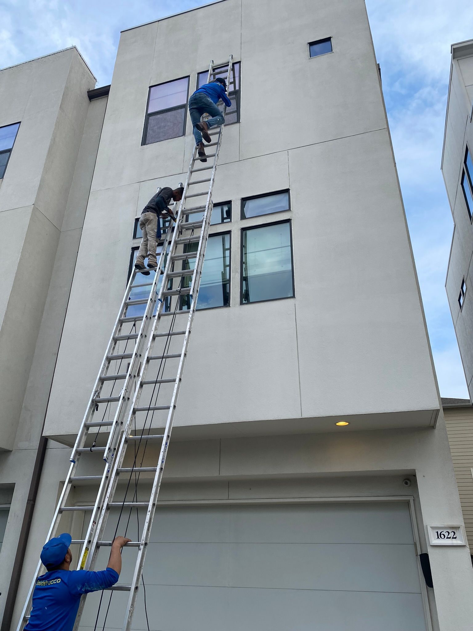 Two men are cleaning windows on the side of a building.