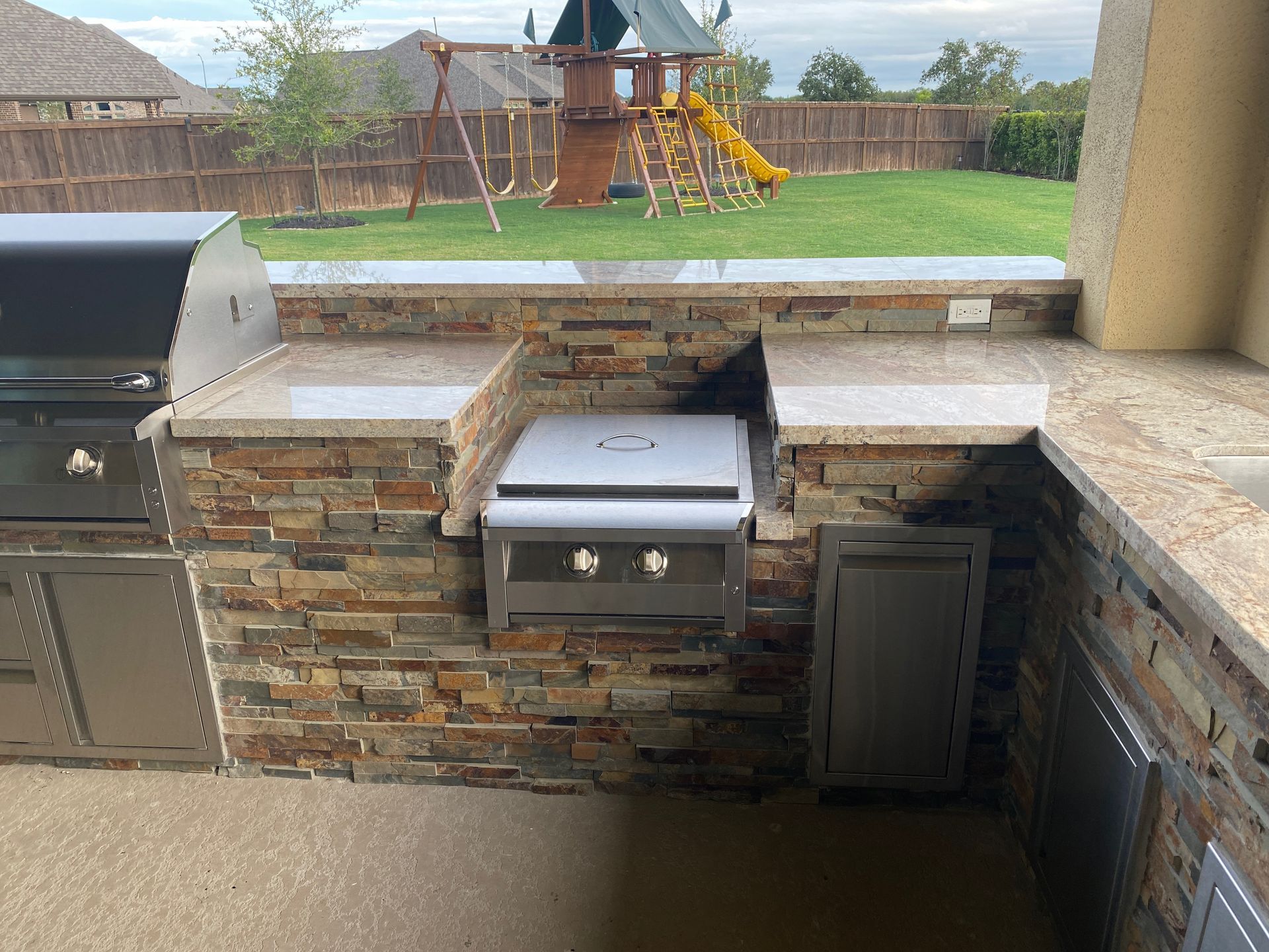 A kitchen with a grill and a playground in the background