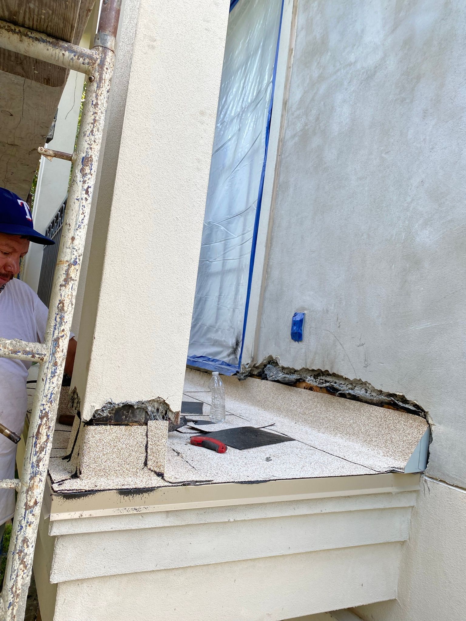 A man is standing on a ladder painting a wall.