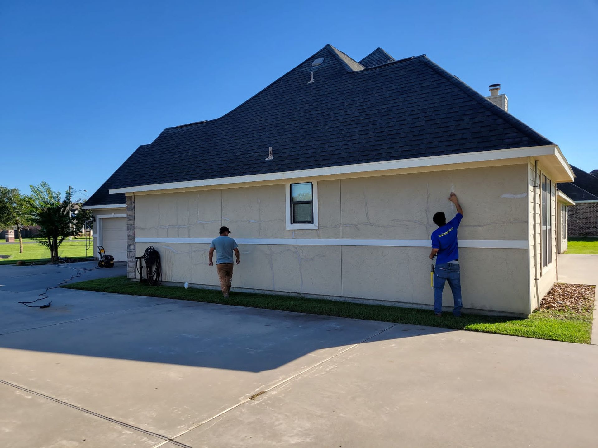 Two men are working on the side of a house.