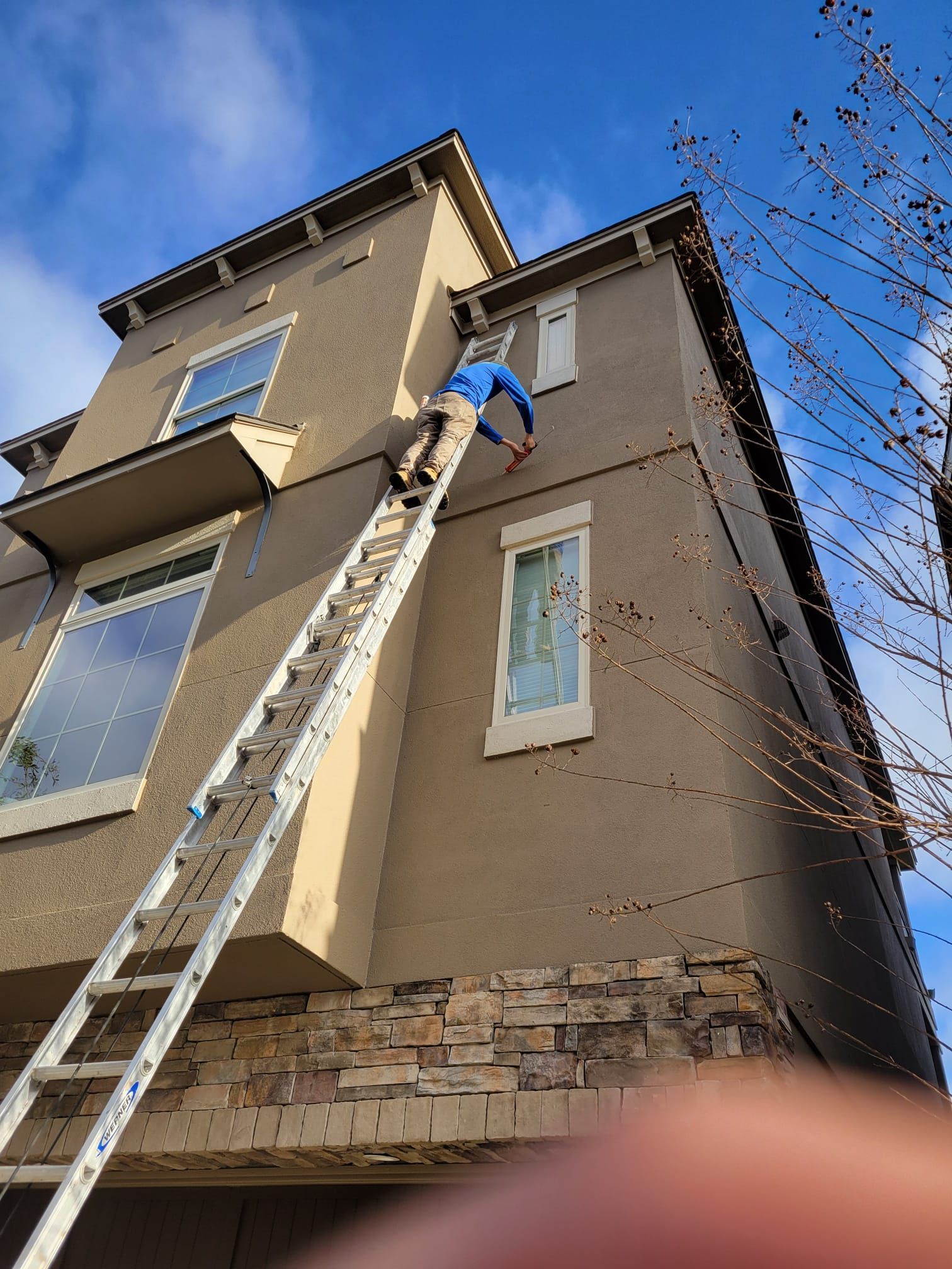A man is standing on a ladder on the side of a building.