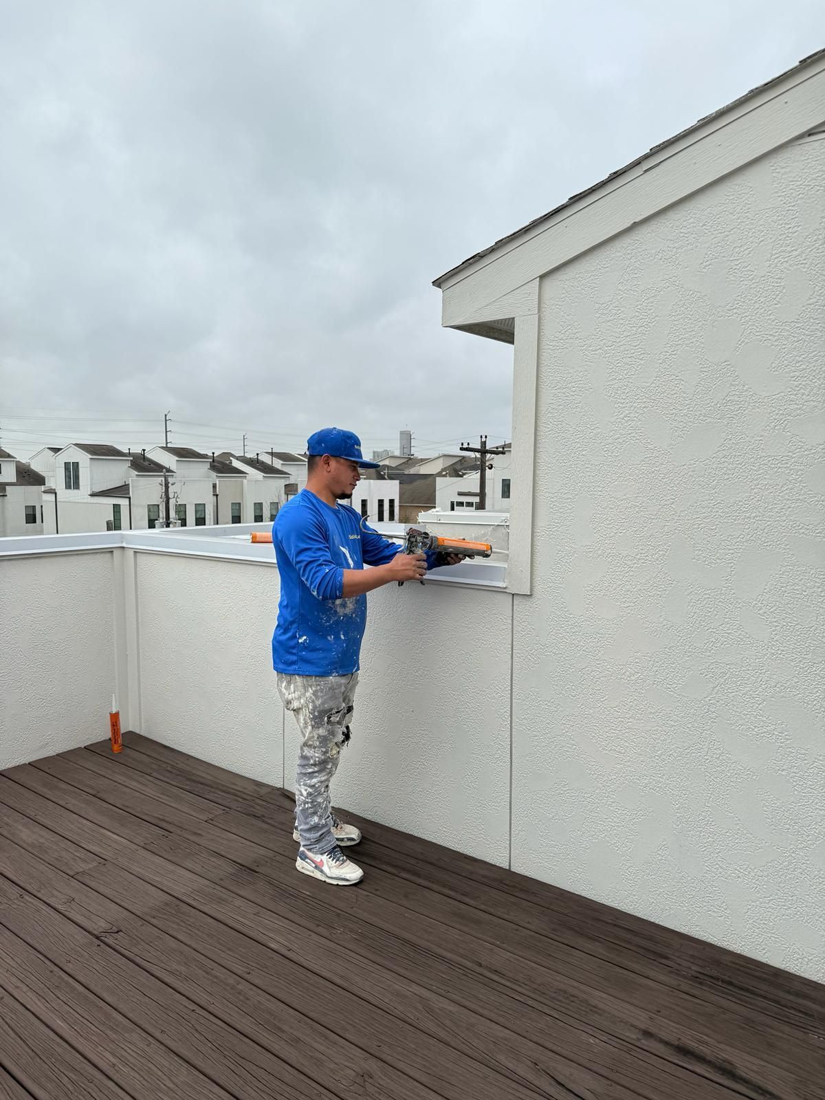 A man is standing on a balcony painting a wall.