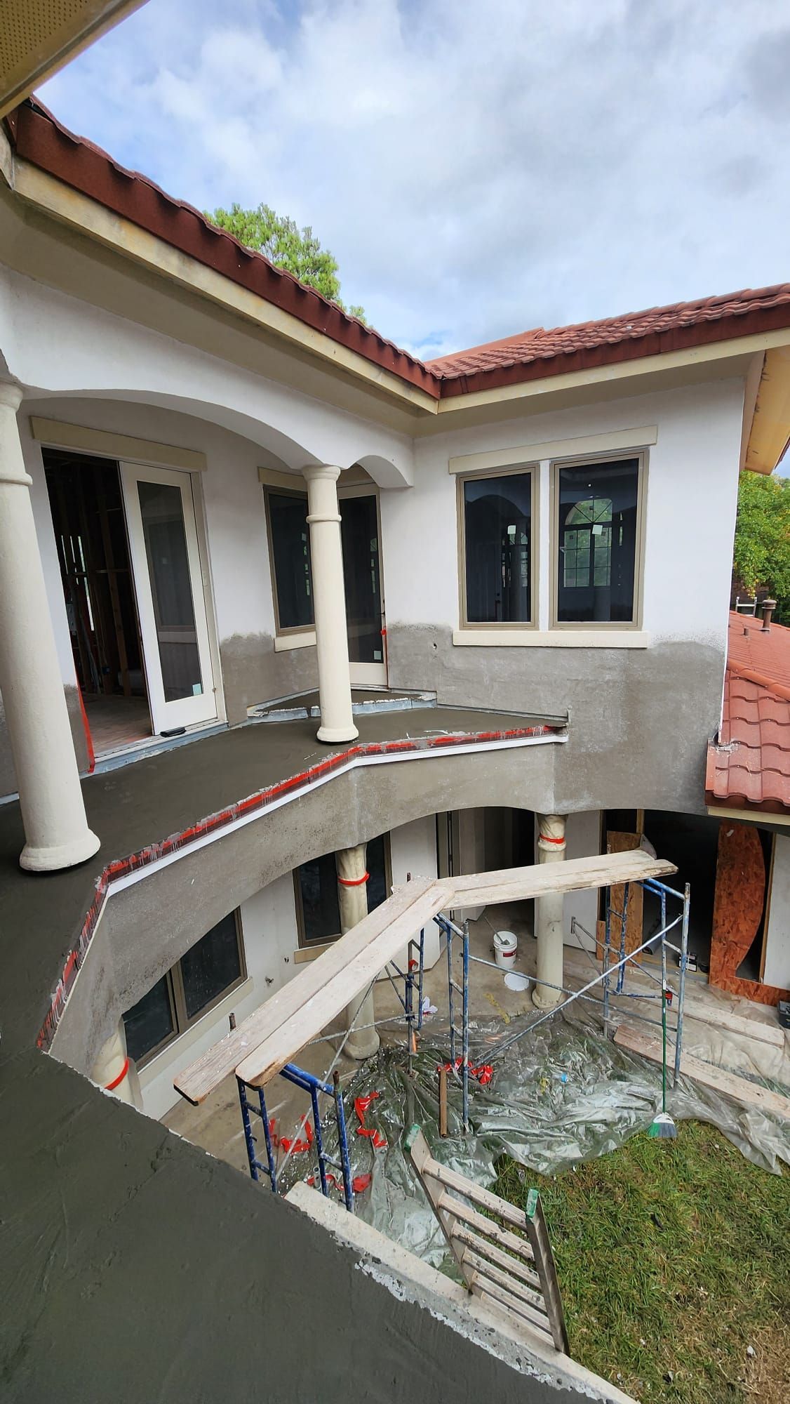 A large white house with a red tile roof is being built.