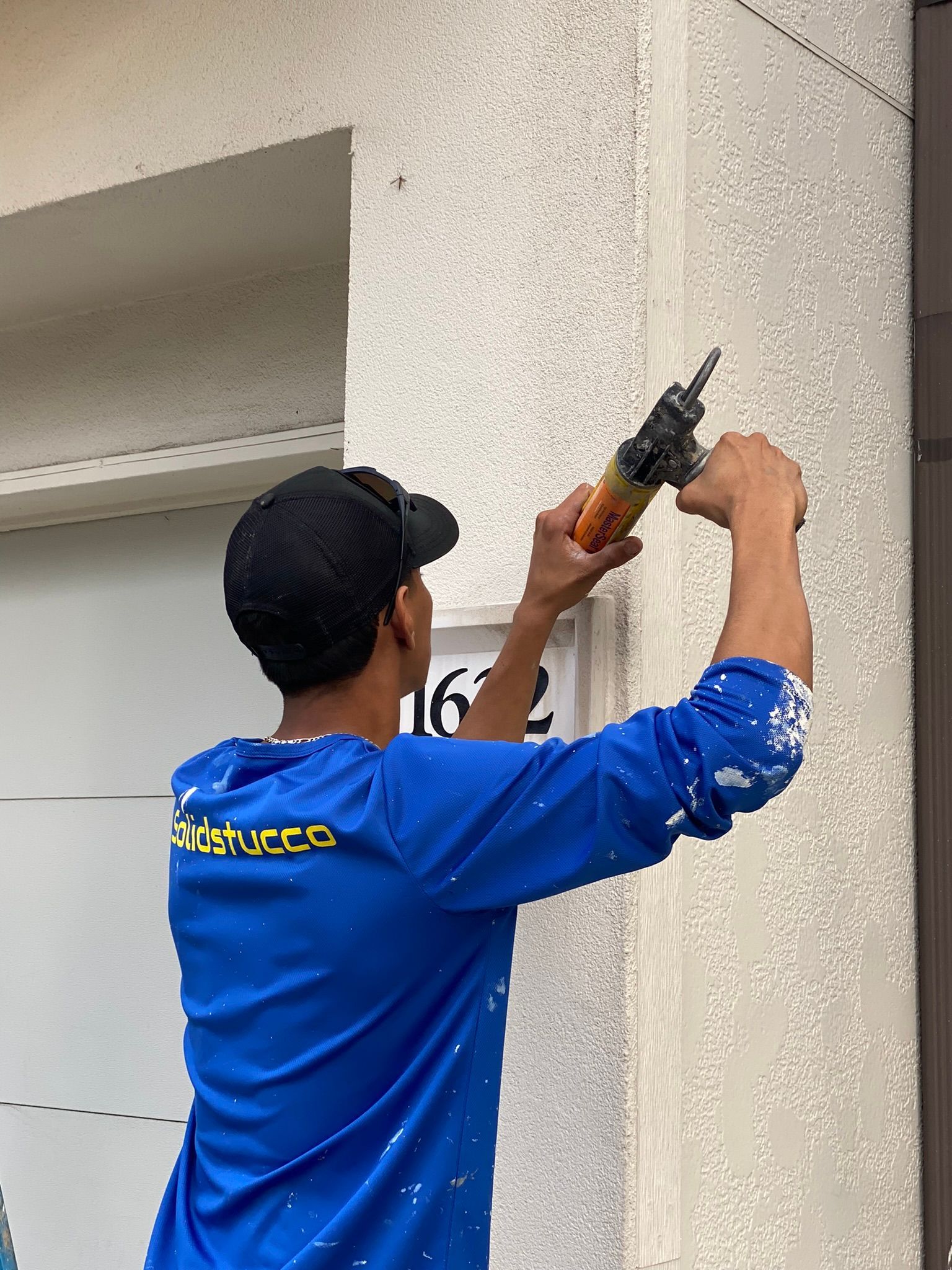 A man in a blue shirt is installing a sign on a wall.
