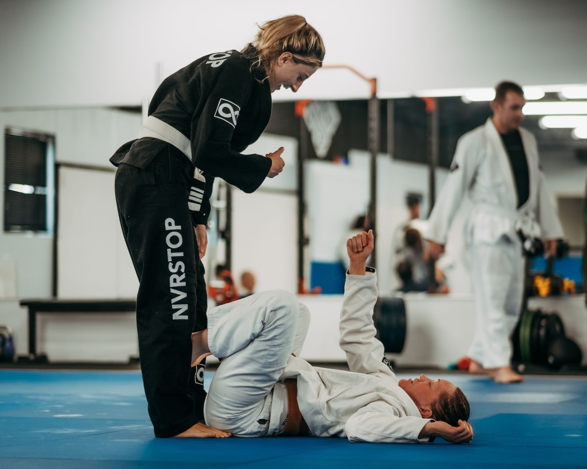 Two martial artists in gis practice grappling on a blue mat in the best martial arts center in Ottawa, ON