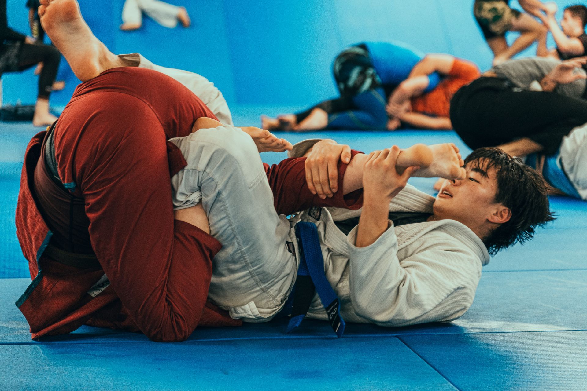 Two people grappling on a blue mat in a martial arts training session at the best martial arts center in Ottawa, ON