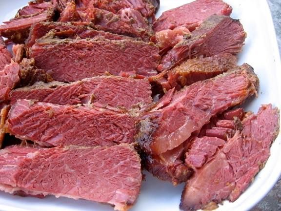 A white plate topped with sliced corned beef