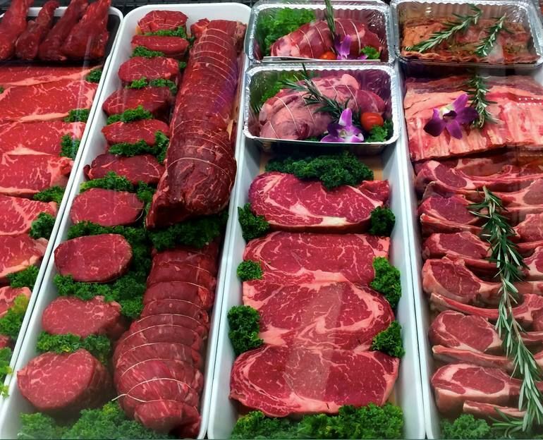 A variety of meats are on display in a butcher shop