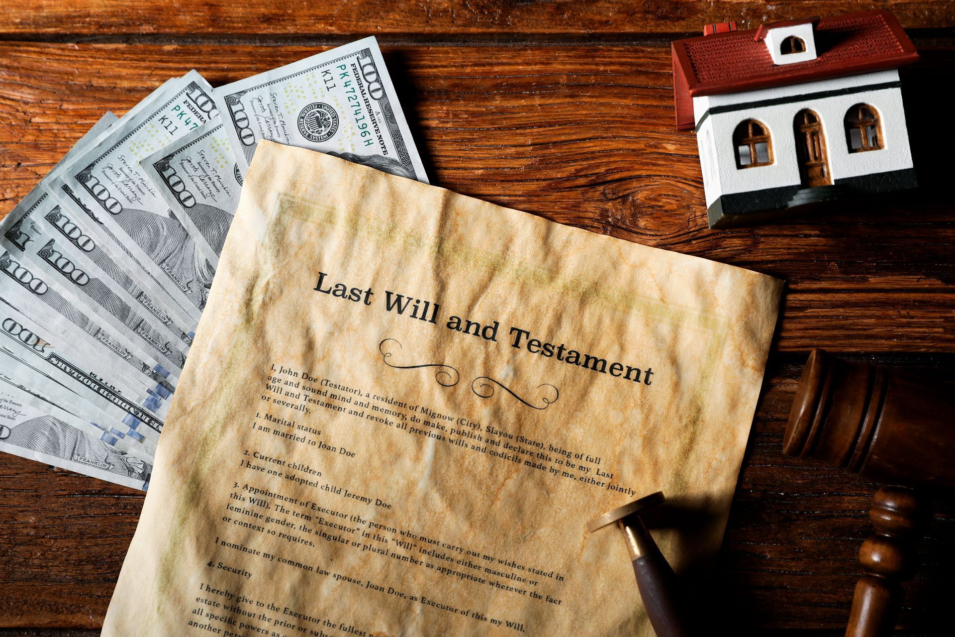 Estate papers and a small house model on a wooden table, with a yellowed document in the center.