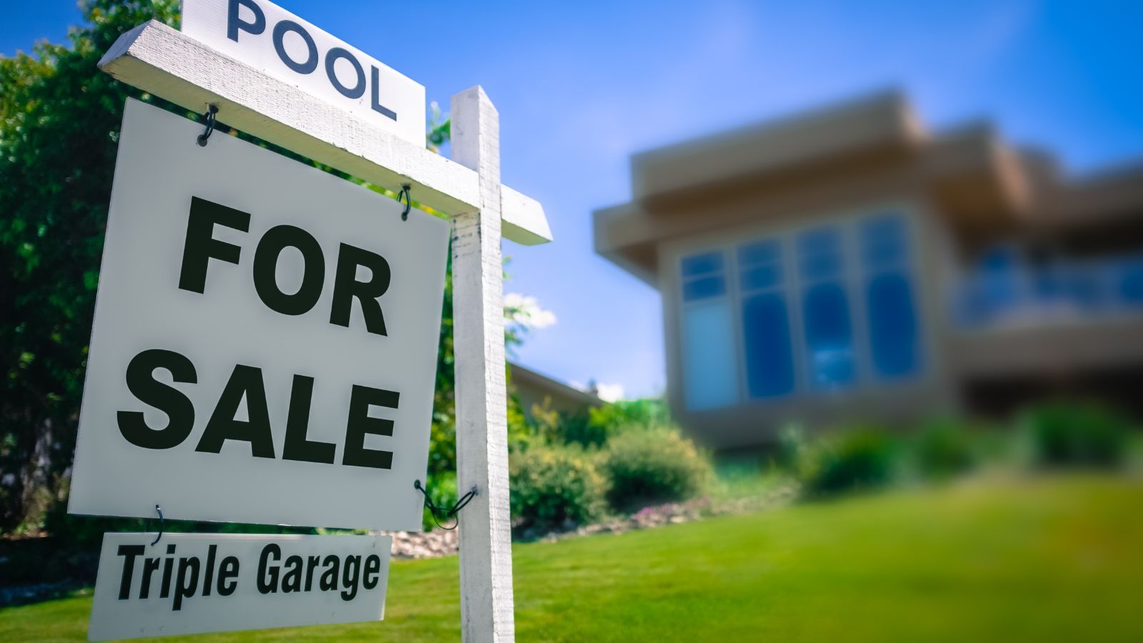 For Sale Sign Featuring a House with a Pool and Triple Garage