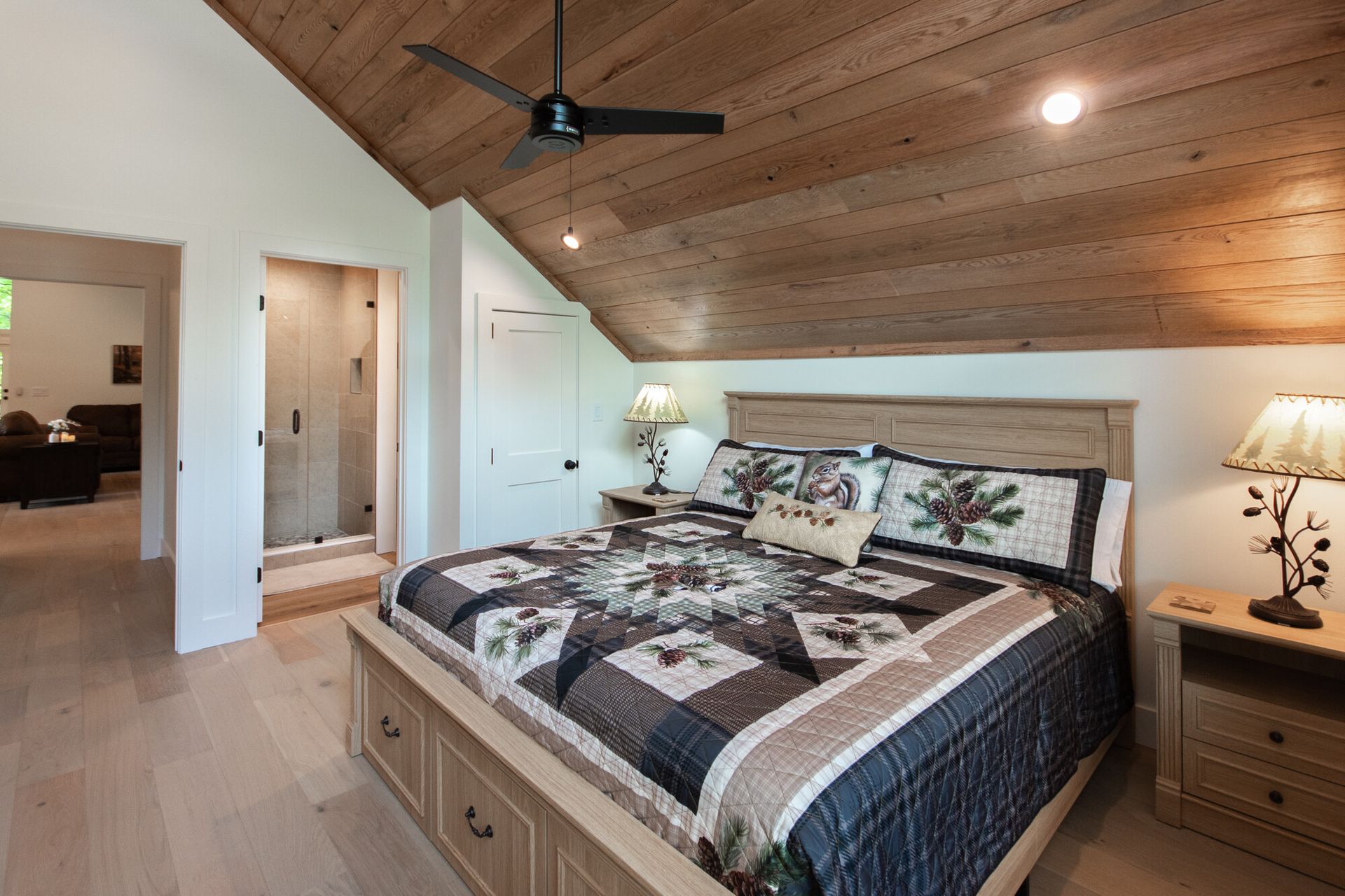 Cozy bedroom with wood ceiling, large bed, bedside lamps, and ceiling fan in a bright, neutral room