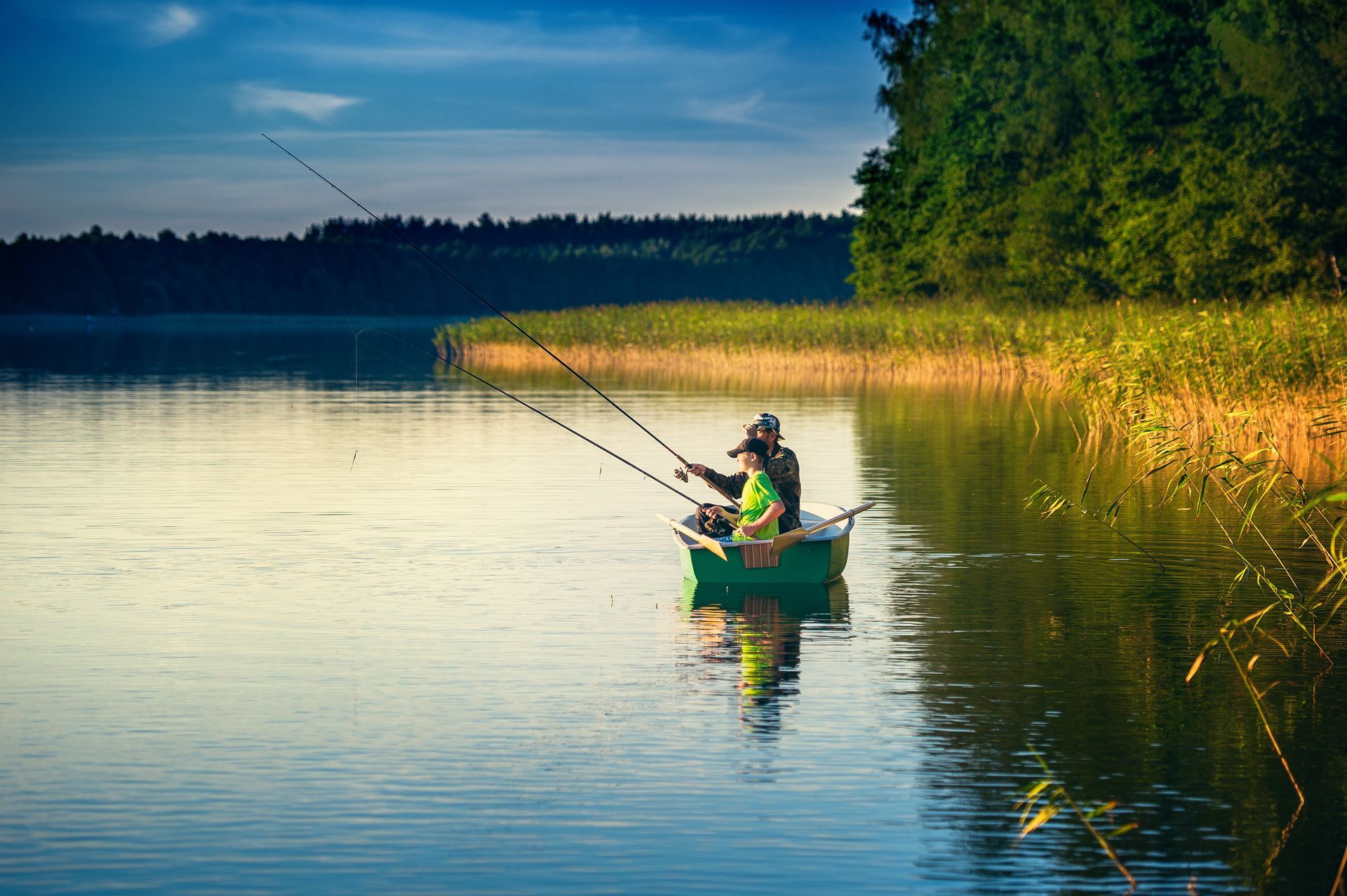 A man and a child are fishing in a boat on a lake.
