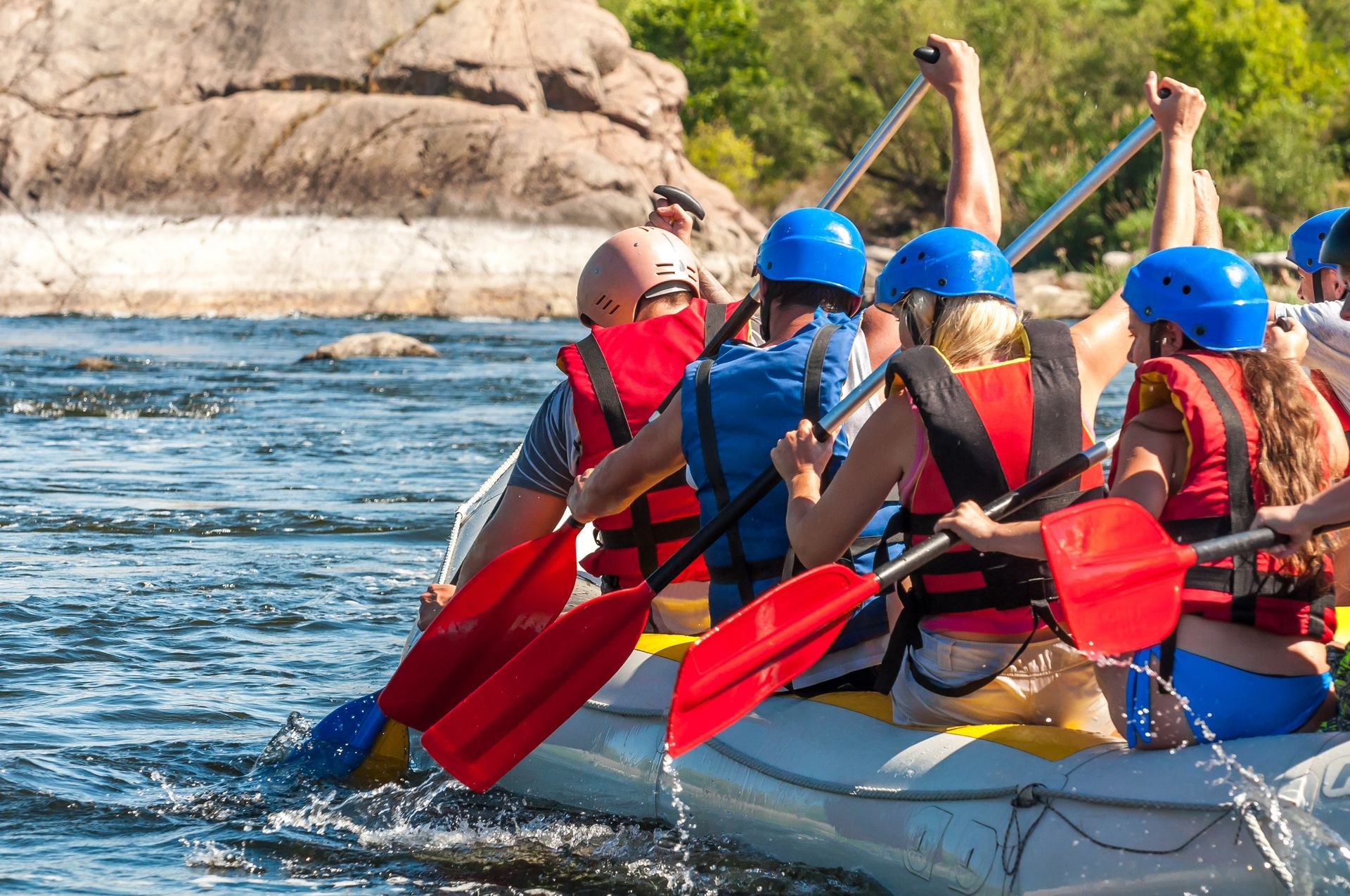 A group of people are rowing a raft down a river.