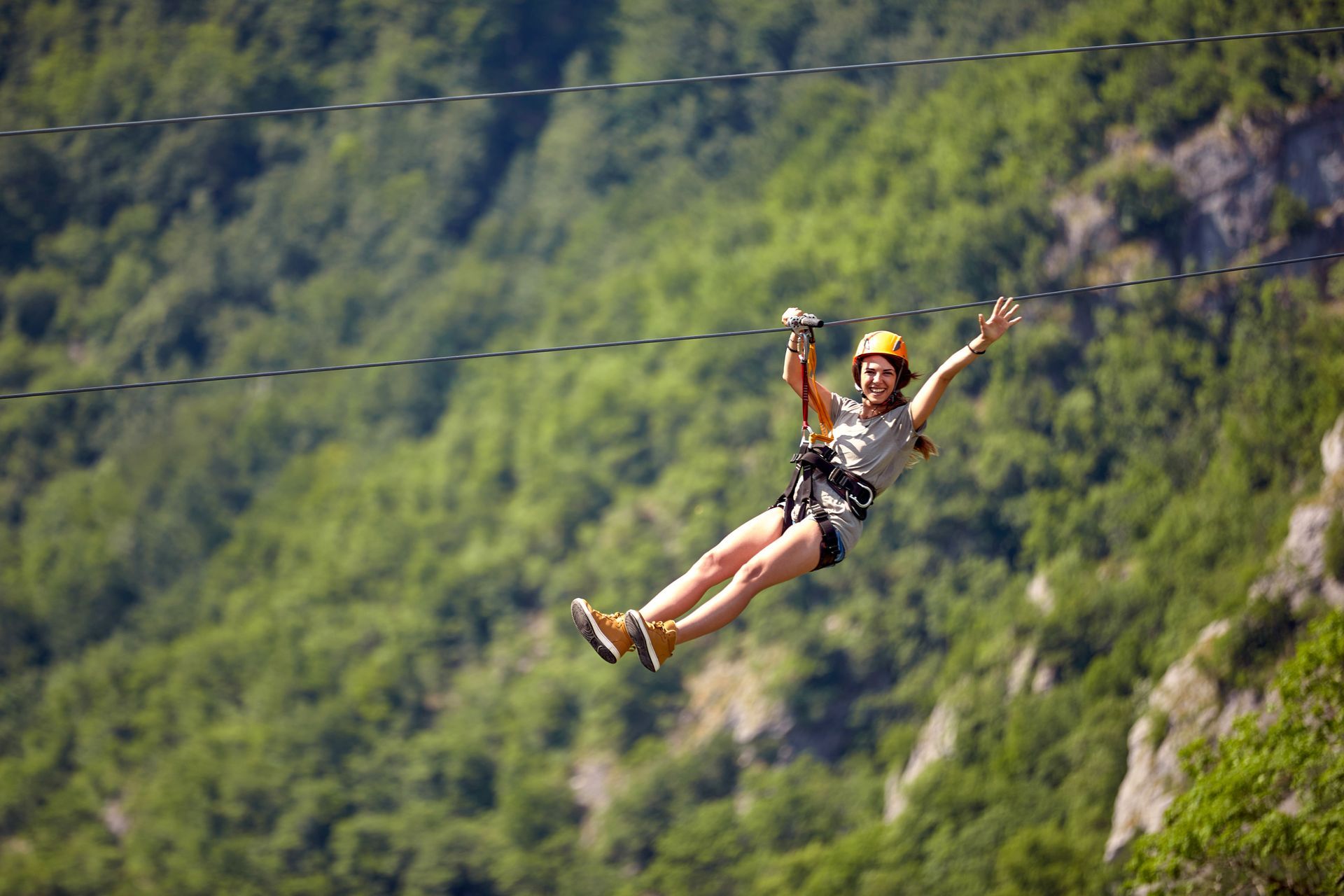 A woman is flying through the air on a zip line.