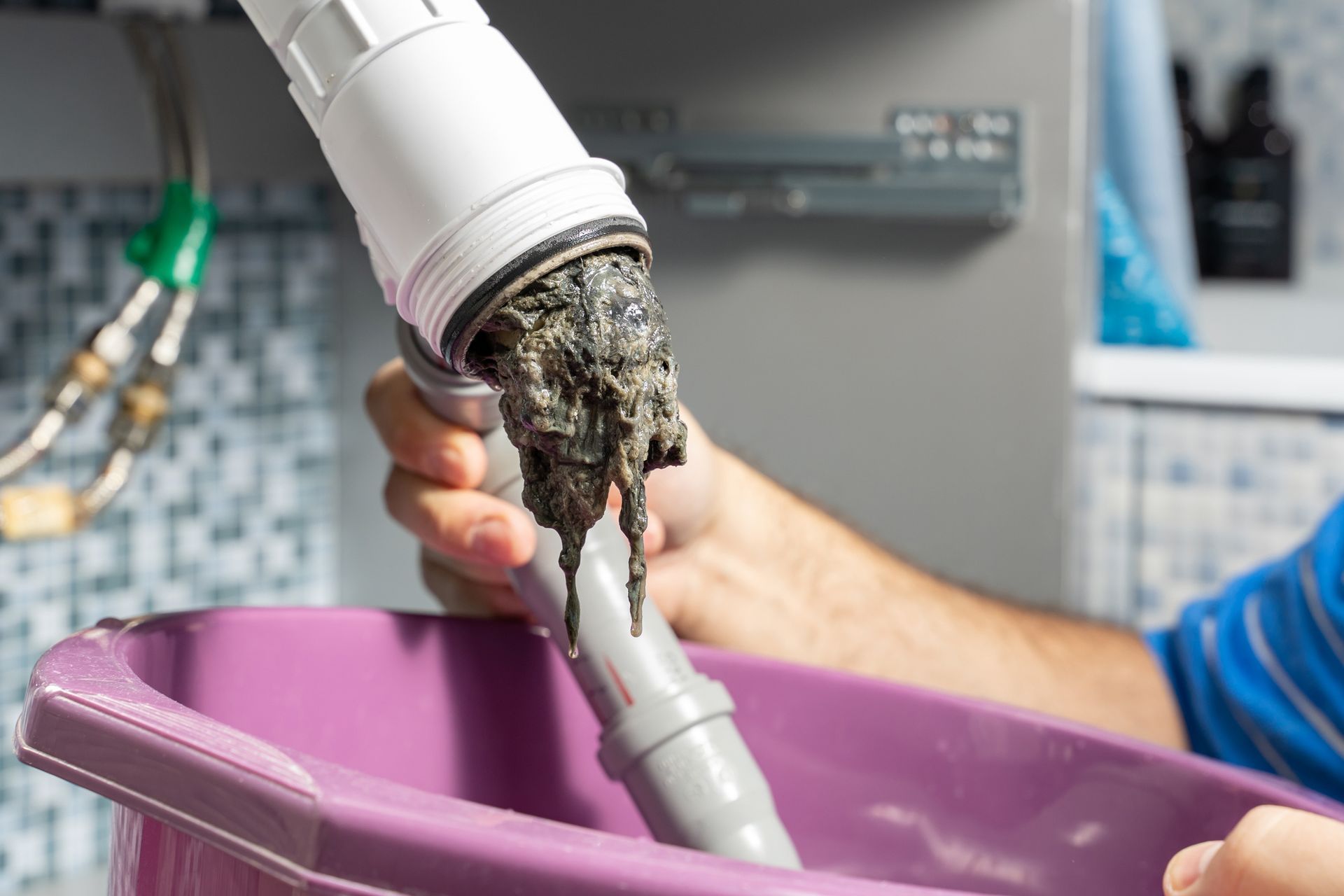 A person is holding a pipe with a lot of dirty water coming out of it.