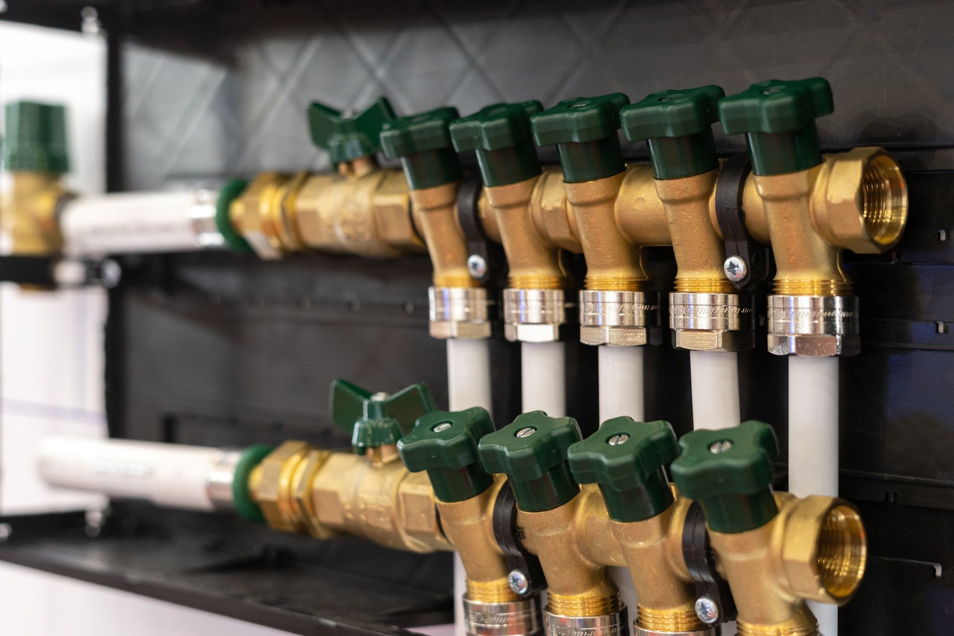 A close up of a row of brass pipes with green valves.
