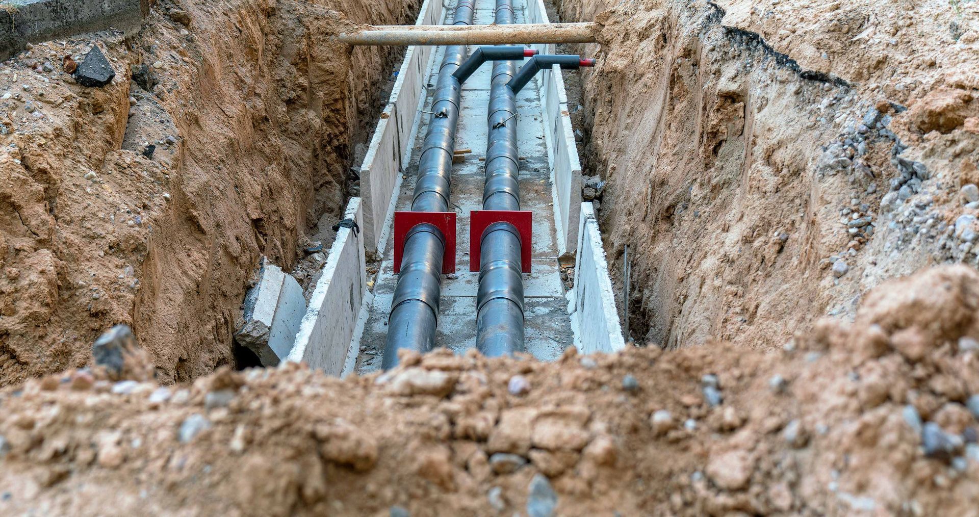 A bunch of pipes are being installed in a trench.