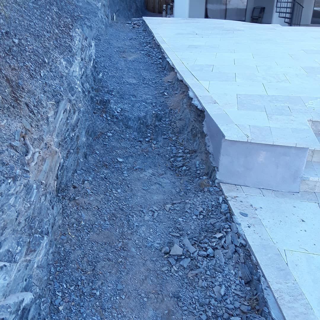 A concrete walkway is being built next to a stone wall