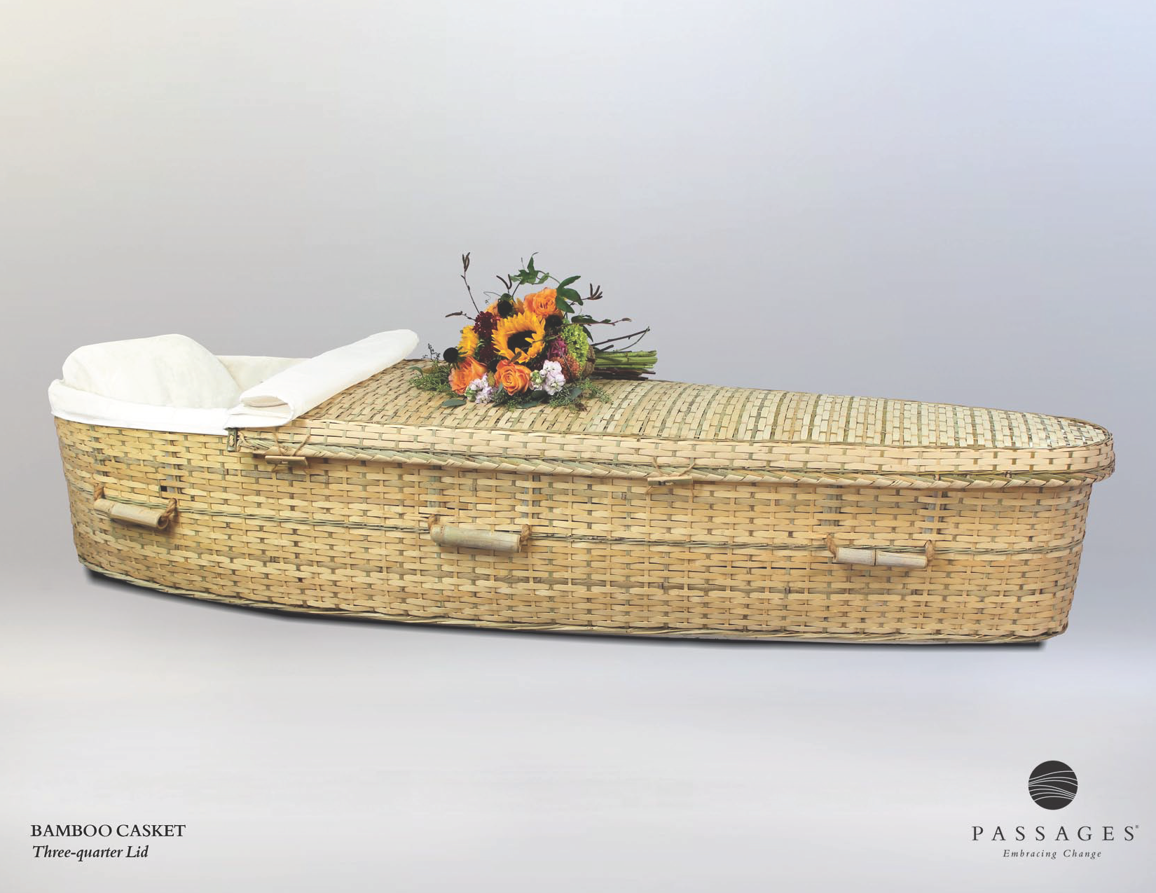 Wicker coffin with floral arrangement, resting on a white background.