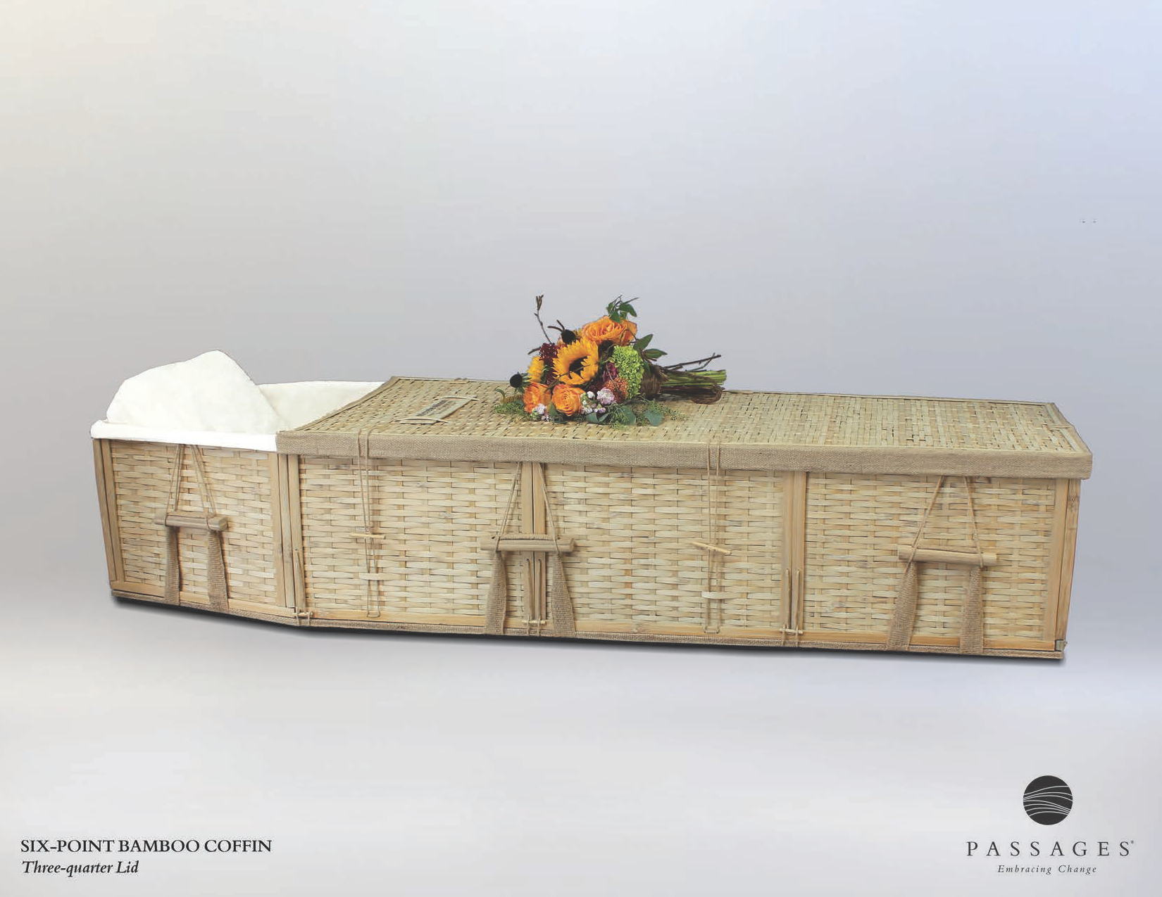 Wicker coffin with flowers on top, set against a plain background.