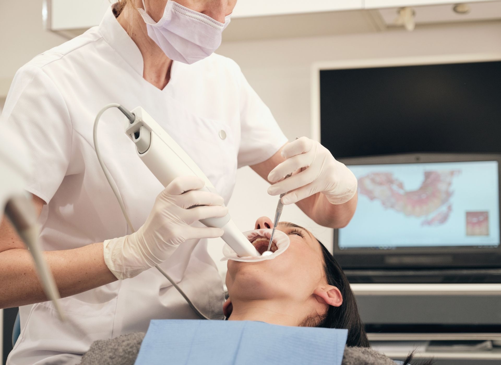 Dental technician using a tool to work on a set of dentures with attached implants.
