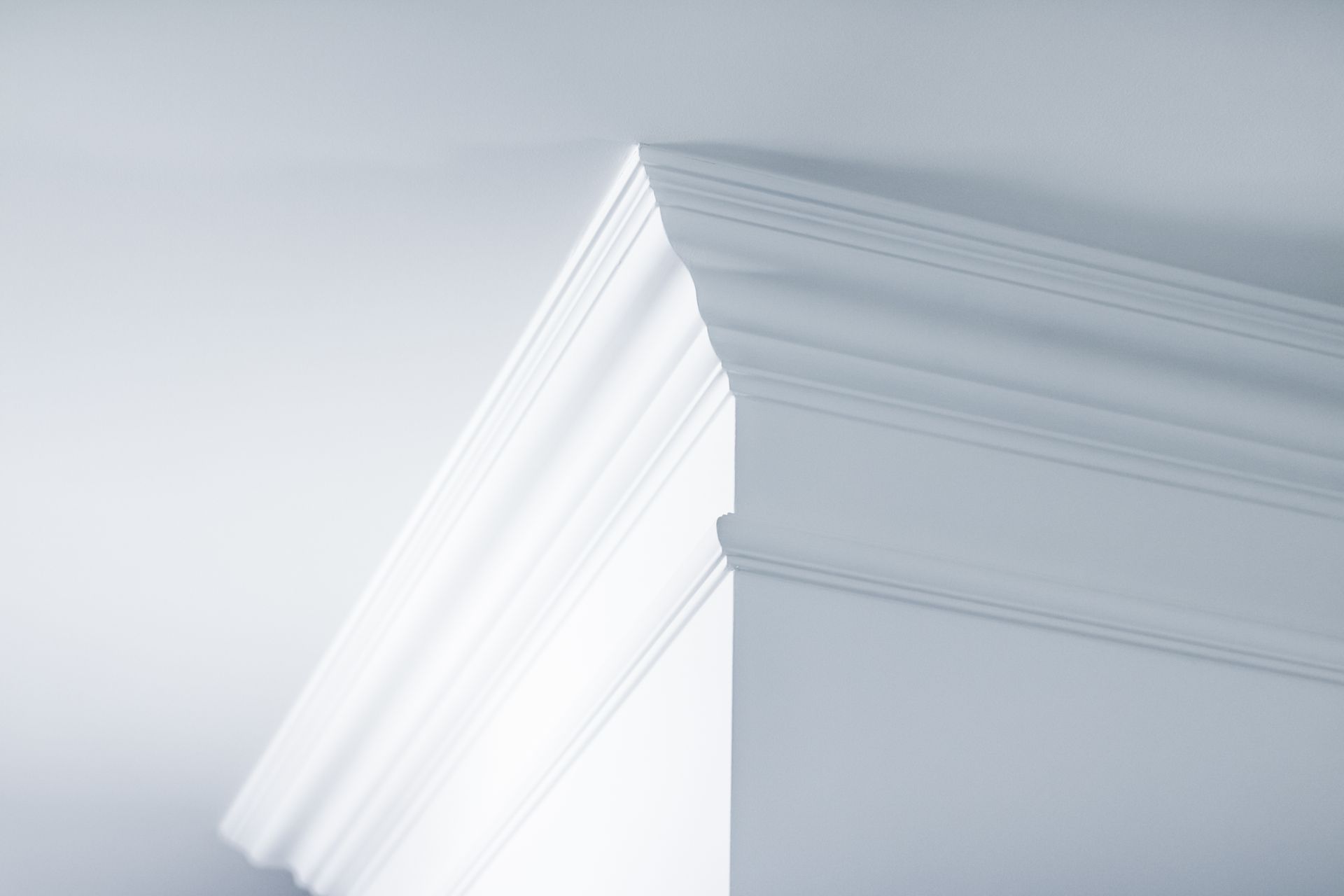 Close-up of white crown molding on a light gray wall corner.