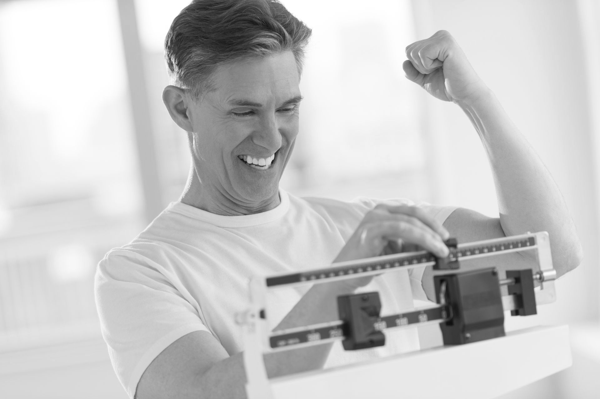Man smiling, flexing arm, looking at scale.