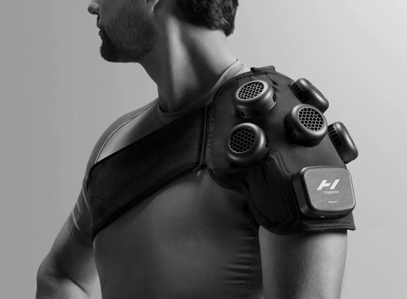 Man wearing a black shoulder support device with circular sensors.
