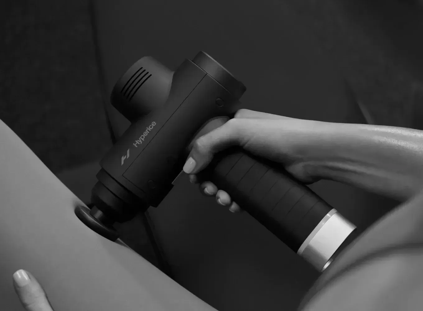 Person using a massage gun on their leg. The device is black.