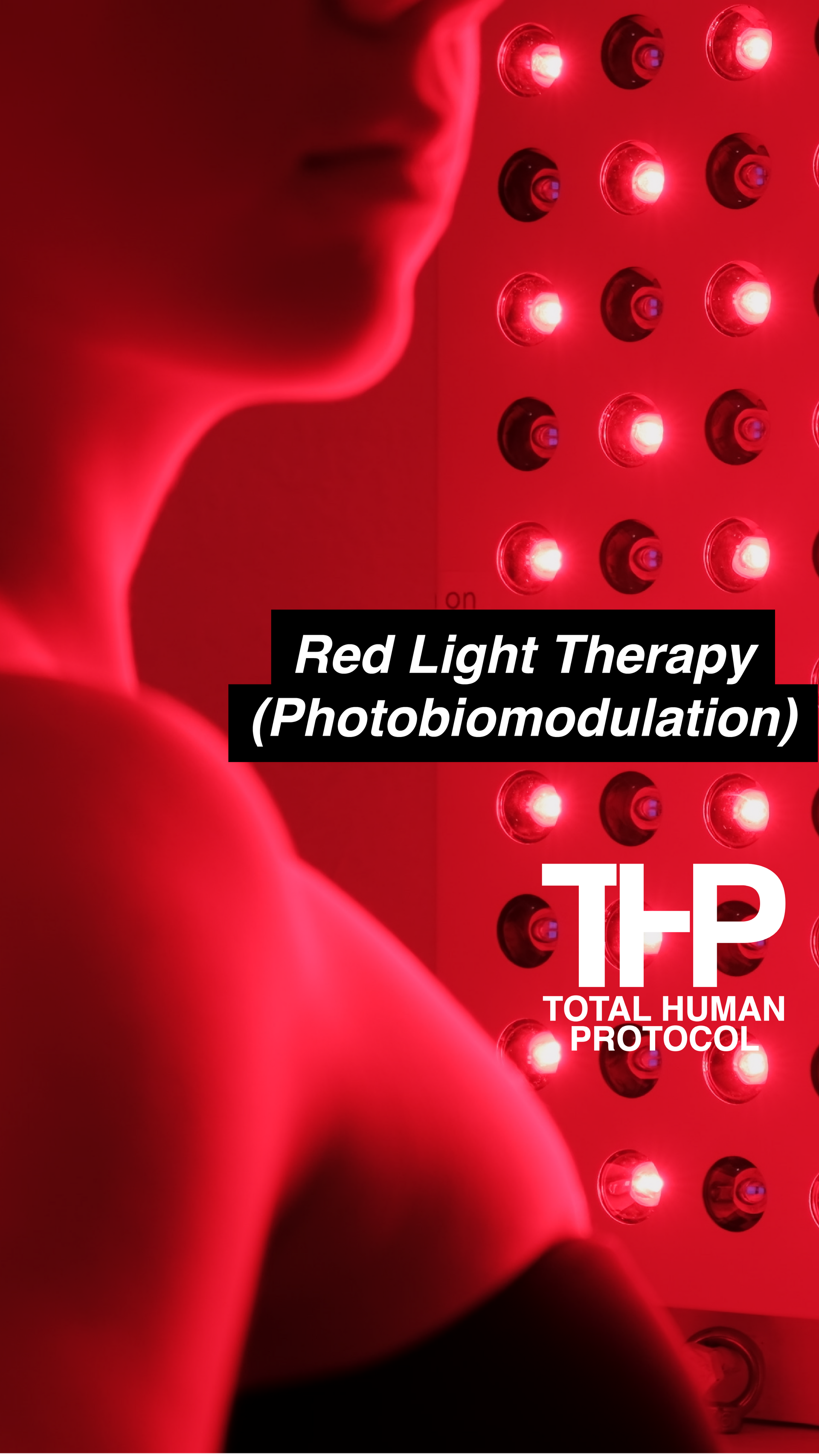 Person using red light therapy panel; illuminated in red light.