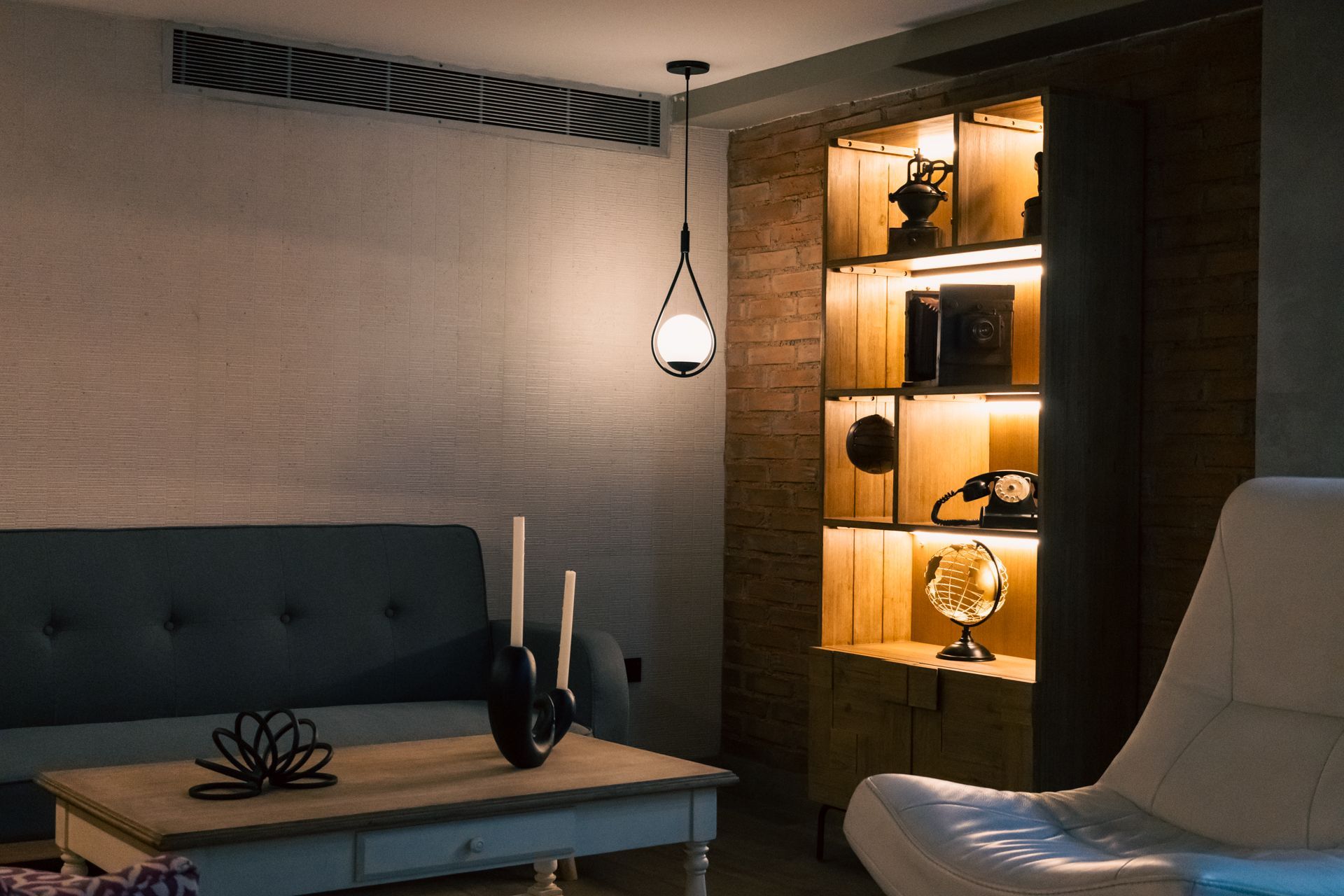 A living room with a couch , table , chair and bookshelf.