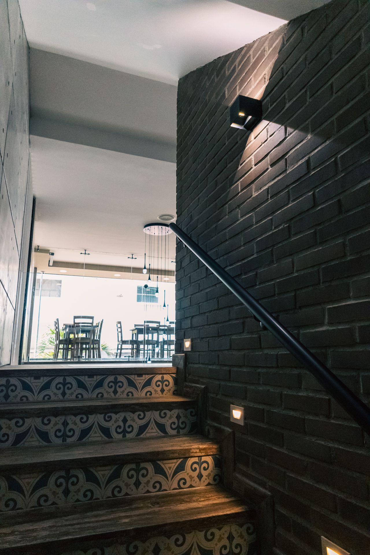A staircase with a brick wall and a black railing leading up to a restaurant.