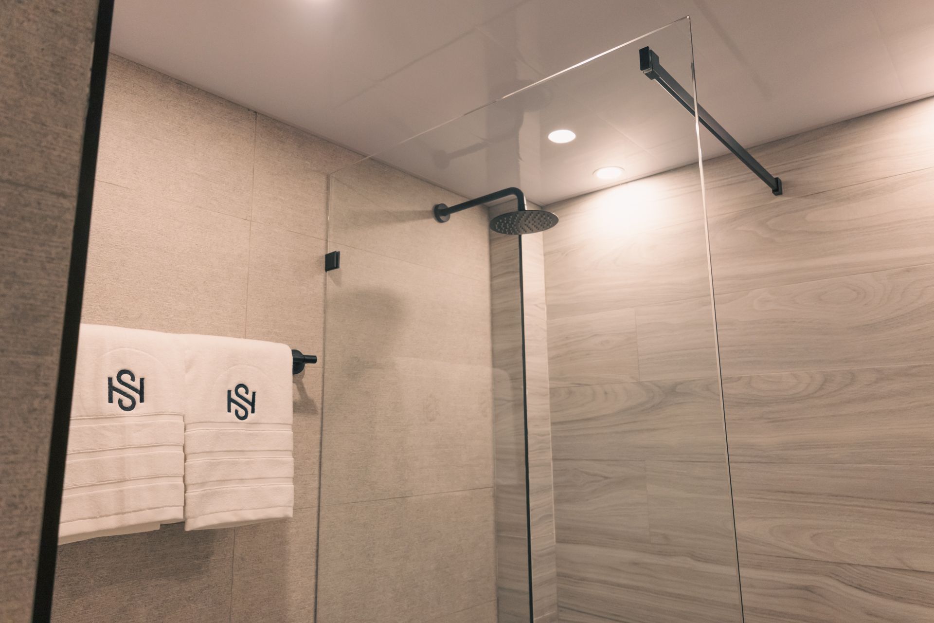 A bathroom with a walk in shower and towels hanging on the wall.