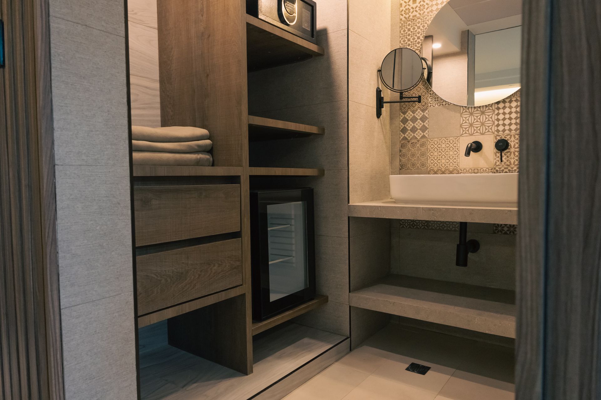 A bathroom with a sink , mirror and a refrigerator.